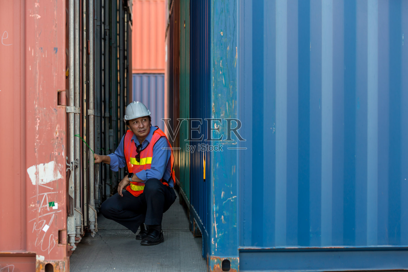 专业的领班在集装箱货场工作，检查集装箱内的货物。工人们正在打开集装箱接受检查。照片摄影图片