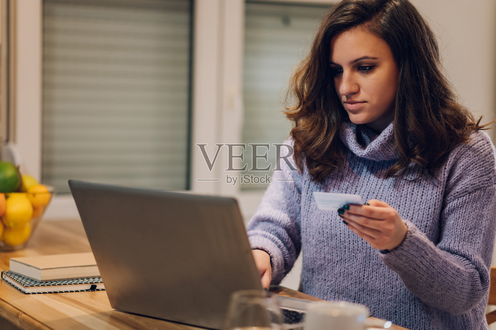 西班牙裔妇女在家里厨房用信用卡用笔记本电脑照片摄影图片