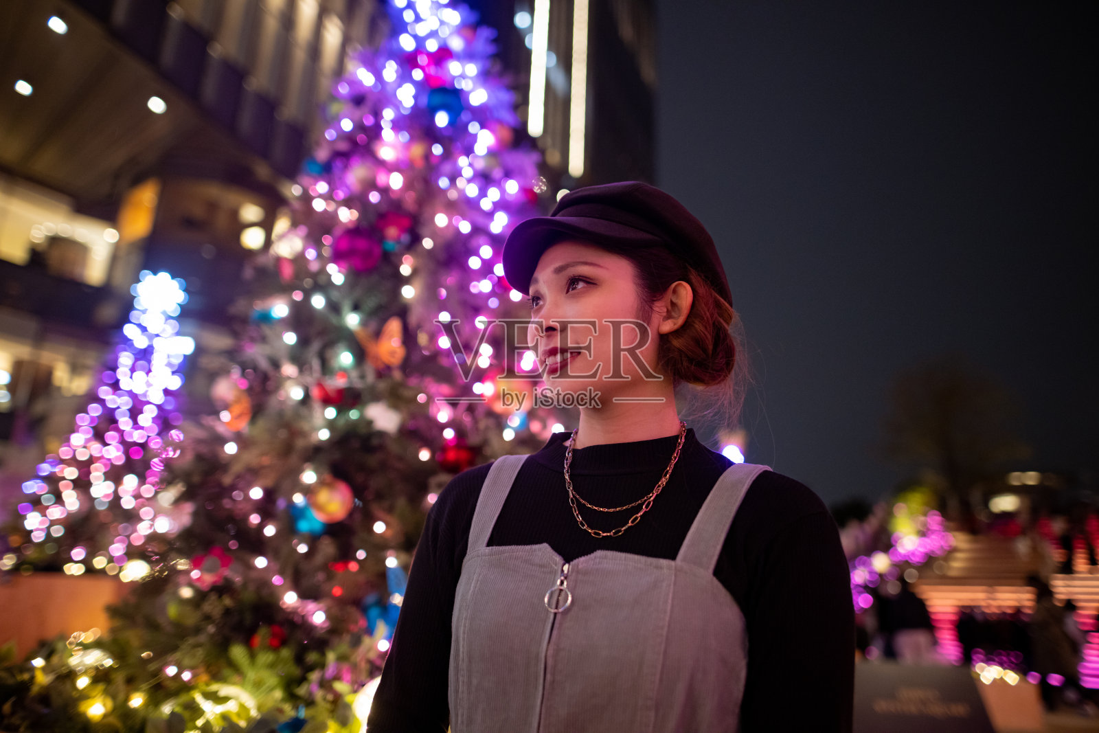 年轻女子站在城市的圣诞树旁照片摄影图片