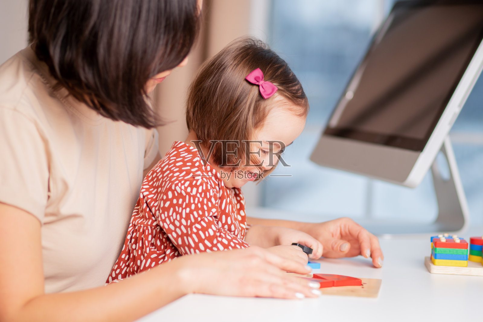 患有唐氏综合症儿童的教育与健康：一位可爱的女孩与一位带着教育玩具的细心母亲照片摄影图片