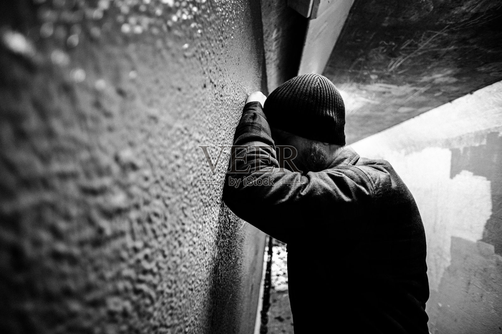 坐在阴冷黑暗地铁隧道里的流浪汉照片摄影图片