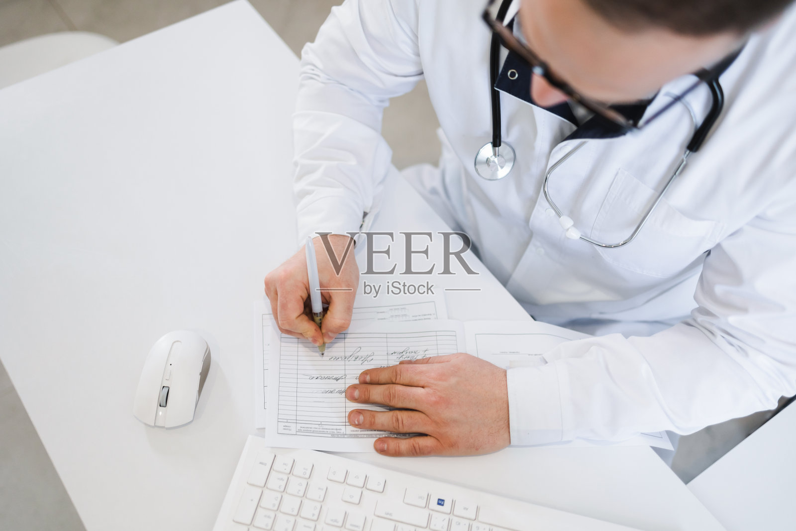 俯视图医生给病人开处方。治疗师在填写一份疾病表格照片摄影图片