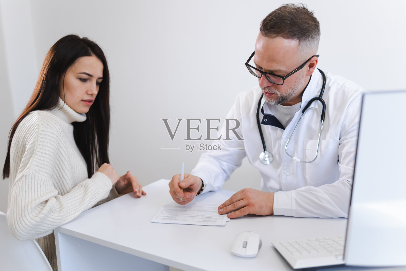 医生给病人开药方。女人去看医生照片摄影图片