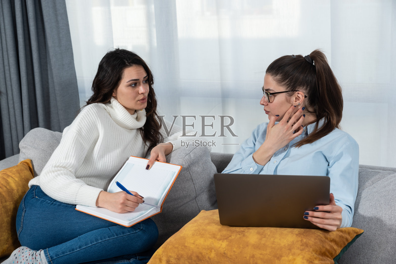 两个年轻的女性小企业主和合作伙伴室内设计师在家工作作为自由职业者，为客户的家庭新设计的想法。女性思考和咨询工作。照片摄影图片