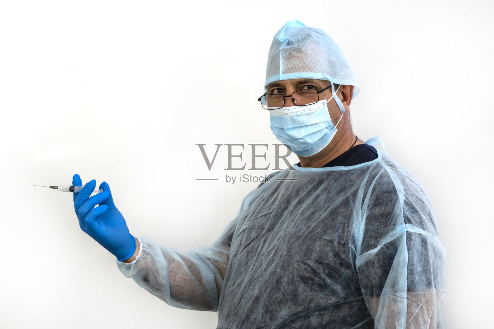 照片中一名医生戴着帽子，手套，拿着注射器照片摄影图片