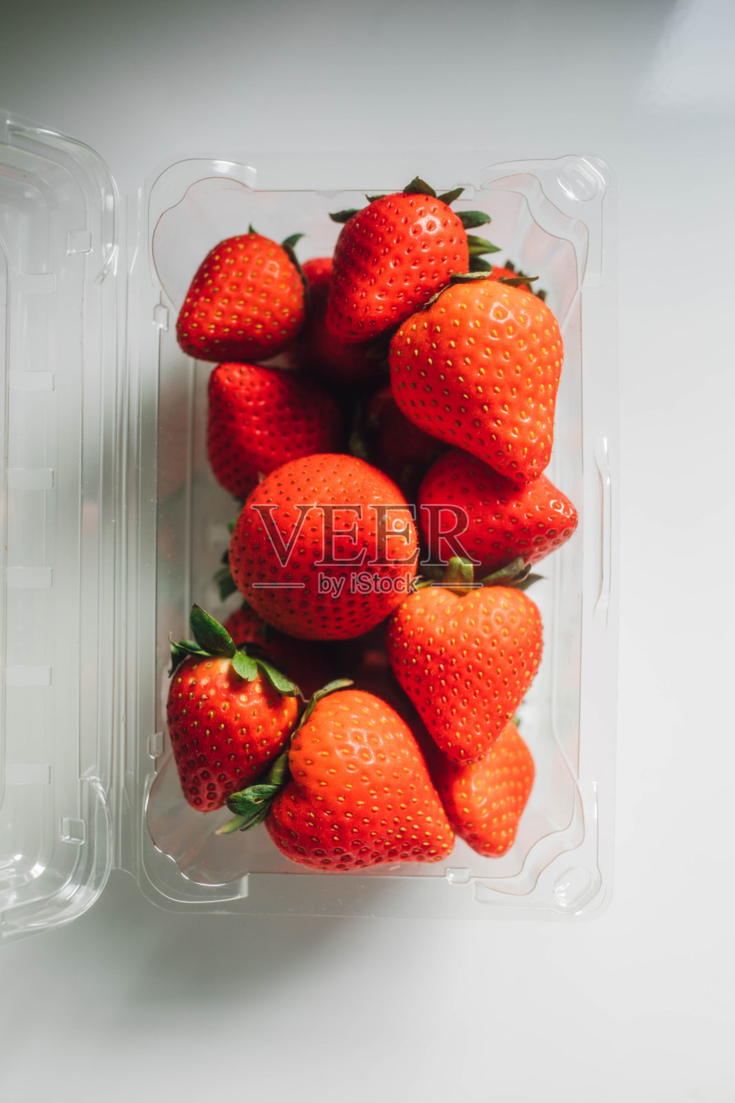 白色的桌子上有一纸盒红草莓照片摄影图片