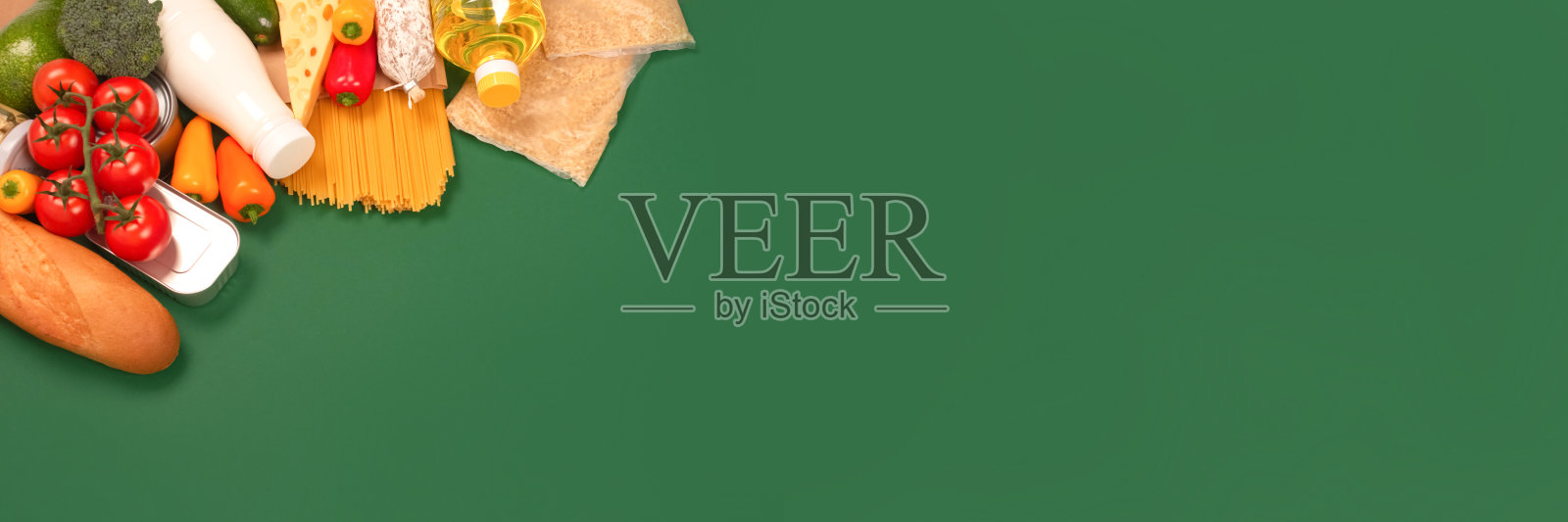 横幅与各种杂货，食品捐赠在绿色背景与复制空间-意大利面，蔬菜，罐头食品，长棍面包，烹饪油，西红柿，奶酪。食物银行或食物递送的概念照片摄影图片