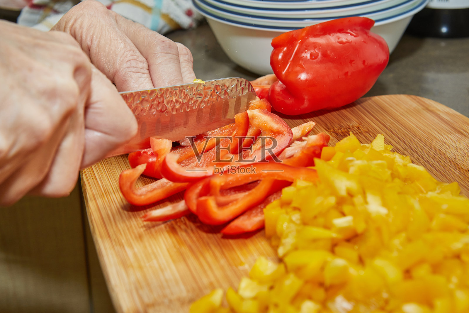 女人在家用菜谱切红黄彩椒照片摄影图片