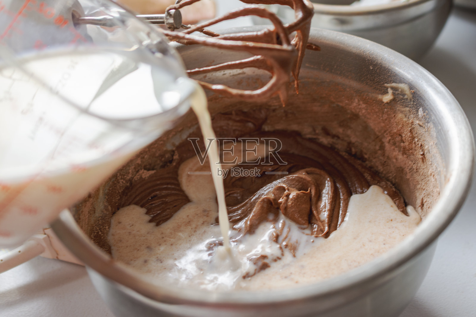 制作巧克力蛋糕:添加额外的牛奶。照片摄影图片