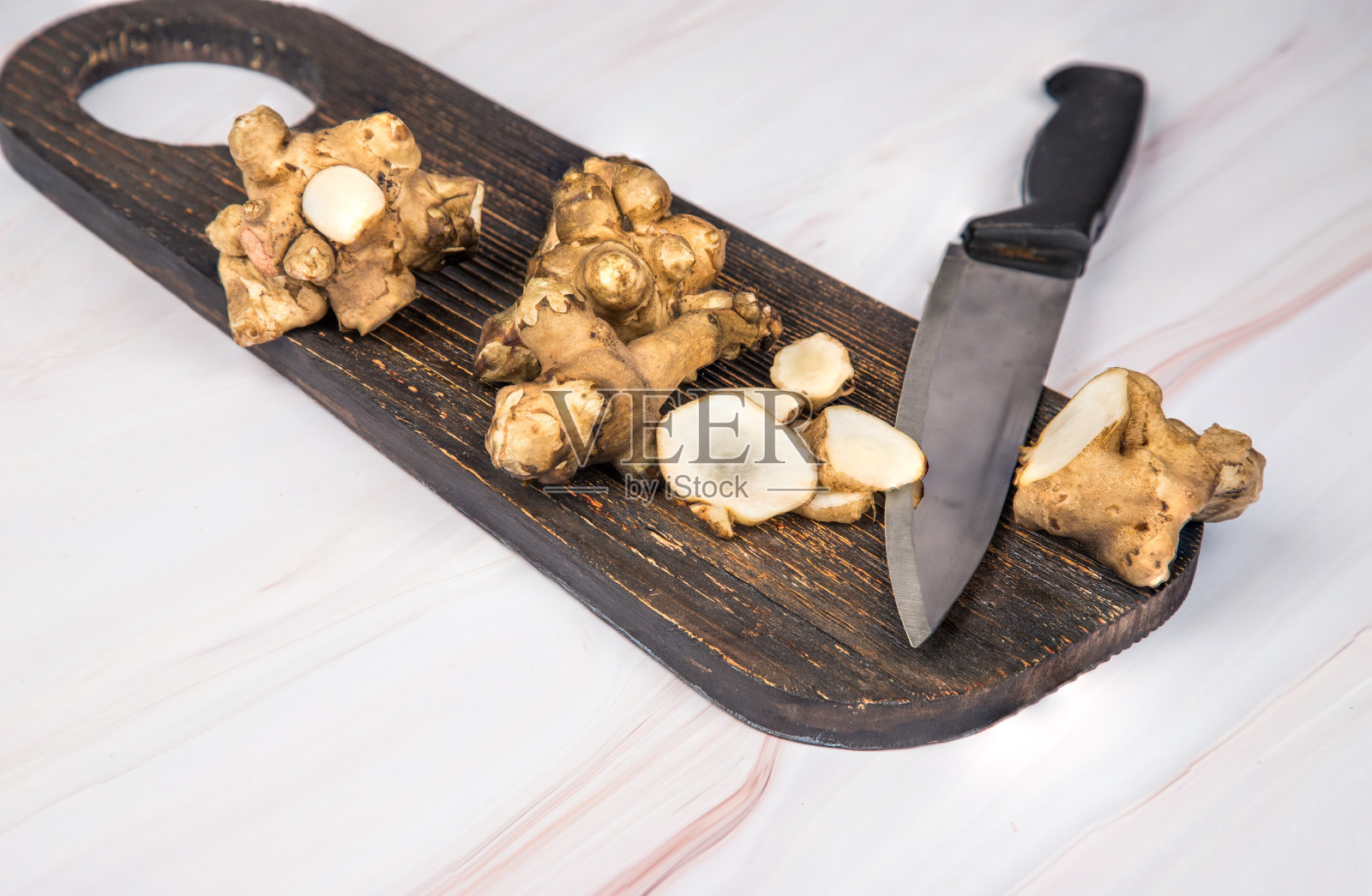 整块切碎的菊芋块茎和刀放在木板上，放在一张轻便的桌子上。照片摄影图片
