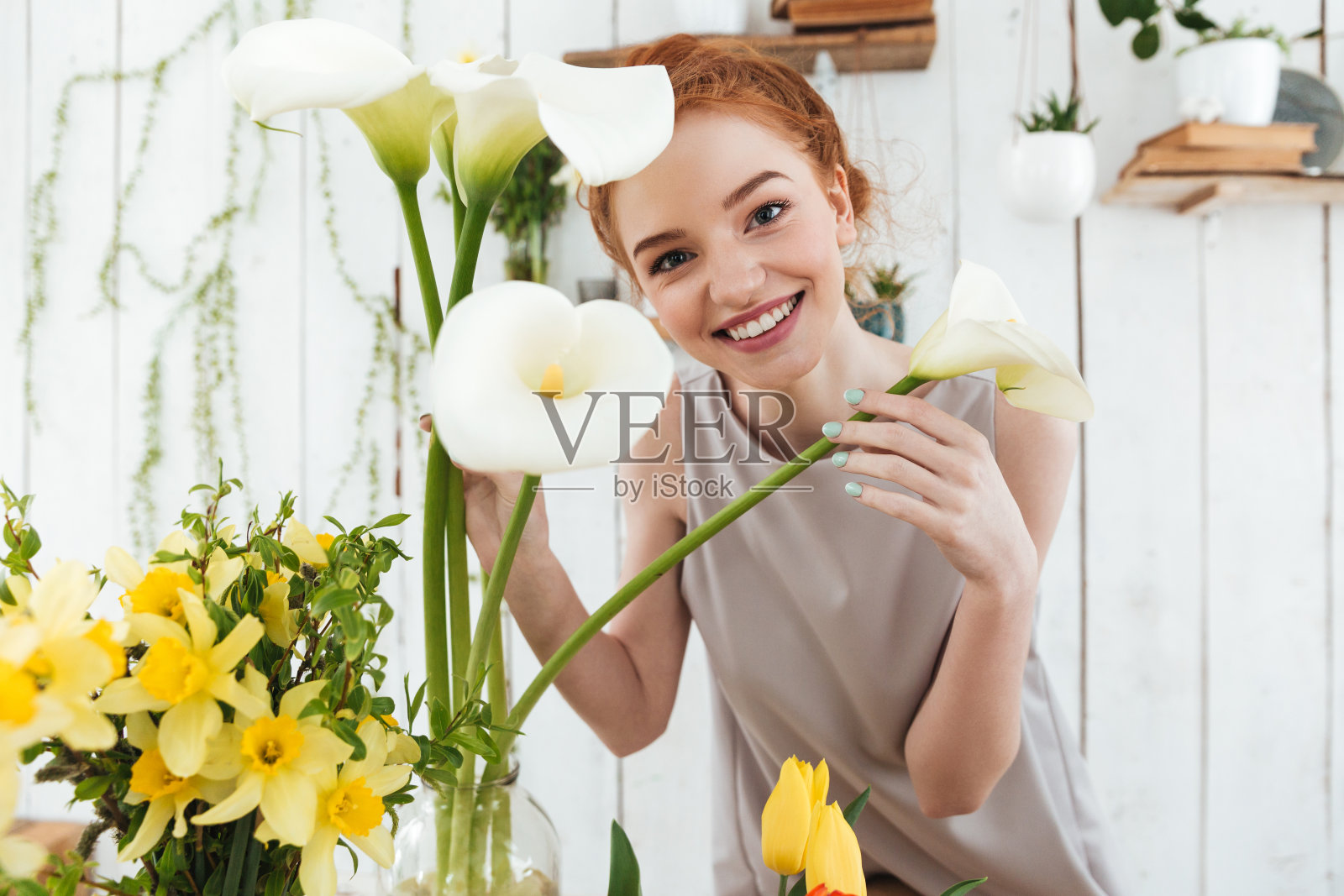 快乐的年轻女士的肖像看着白色的花，而工作照片摄影图片