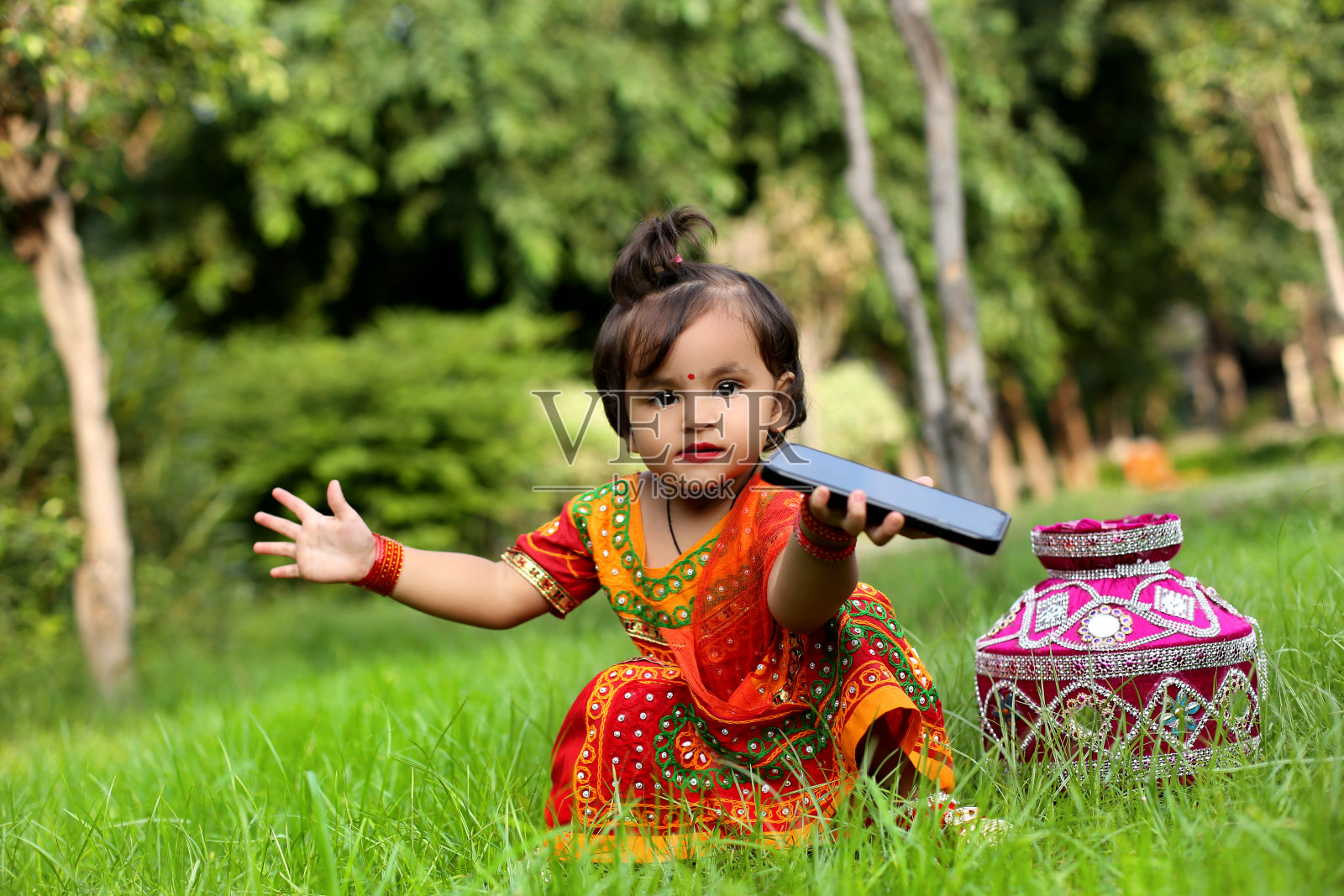 小女孩用手机和她坐在公园外面照片摄影图片