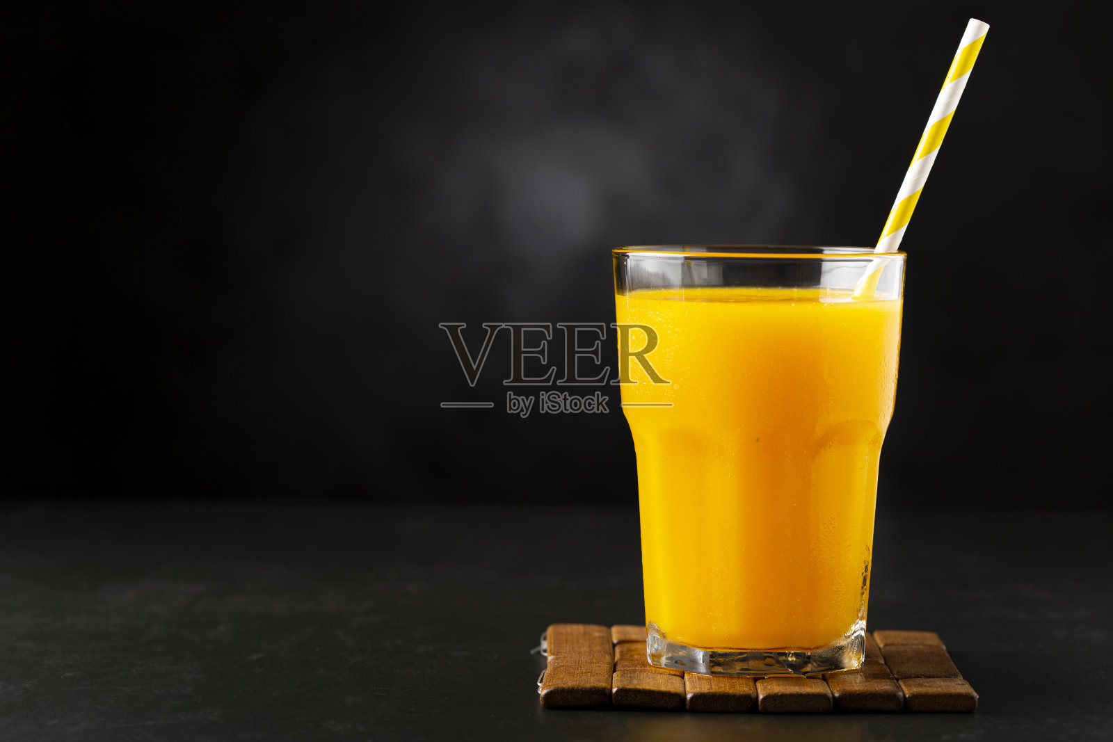 桌上的玻璃杯里有芒果汁。芒果冰沙。照片摄影图片