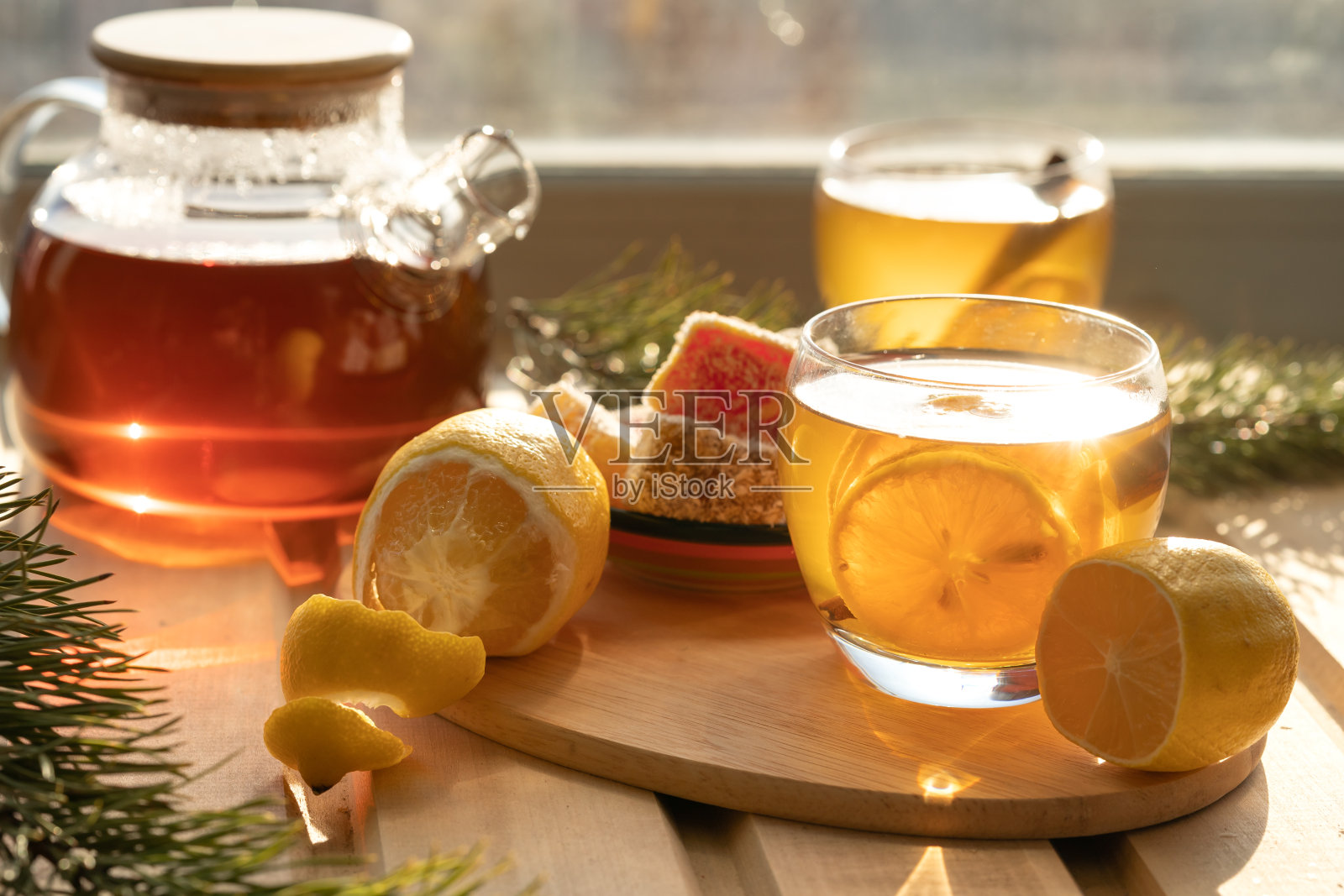 本品用玻璃茶壶和玻璃杯盛满柠檬茶。木桌上的柠檬花草茶茶壶，淡雅的背景。照片摄影图片