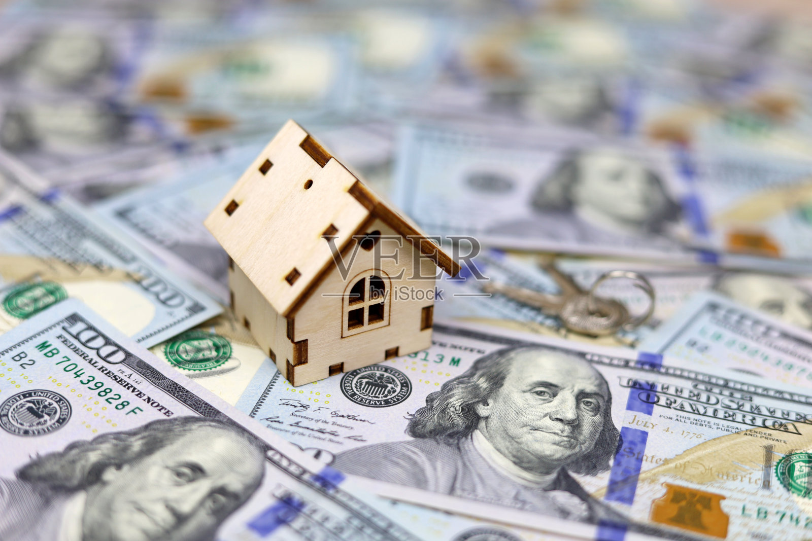 木制房子模型和钥匙的背景上的美元钞票照片摄影图片