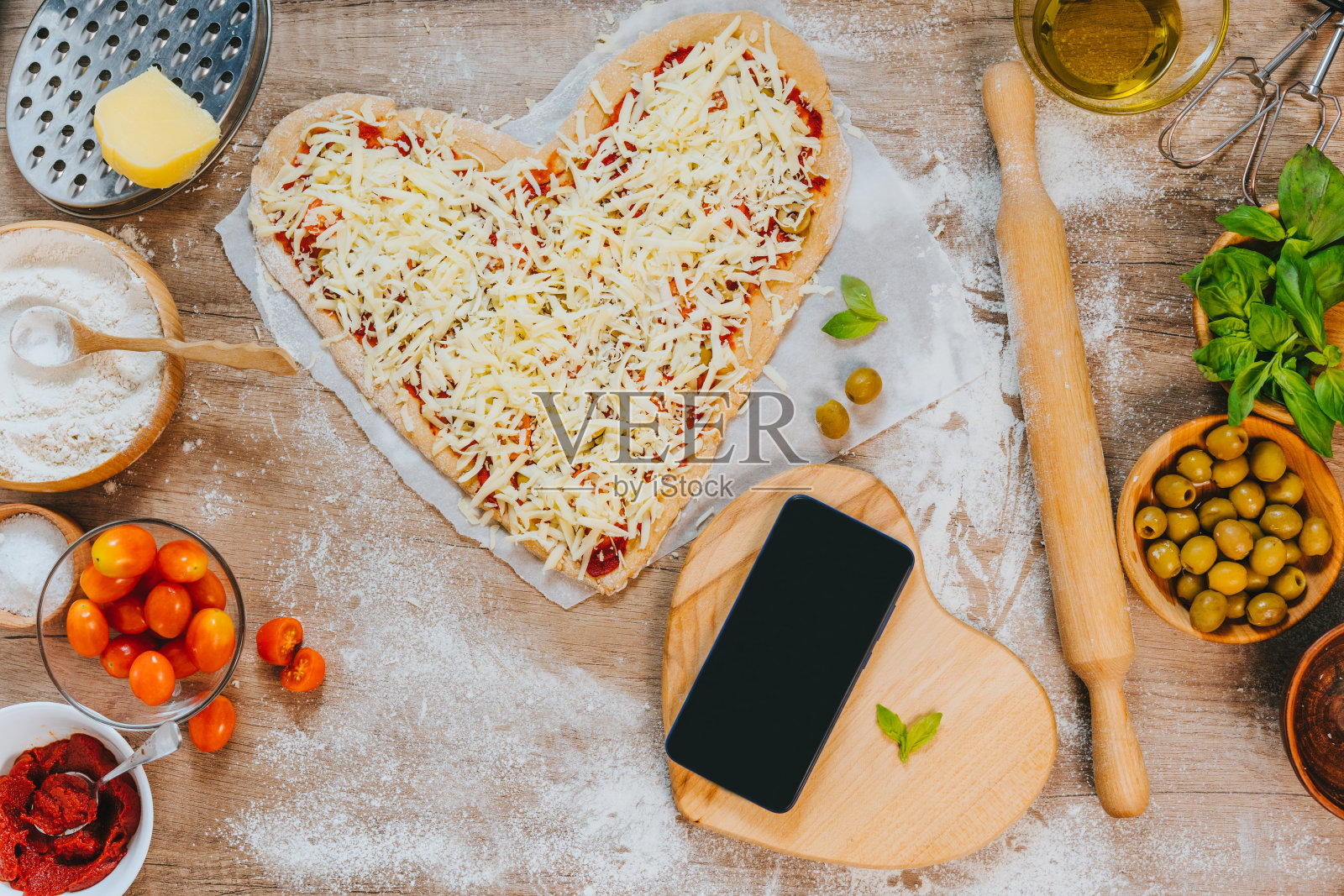 智能手机旁边的心形自制披萨照片摄影图片