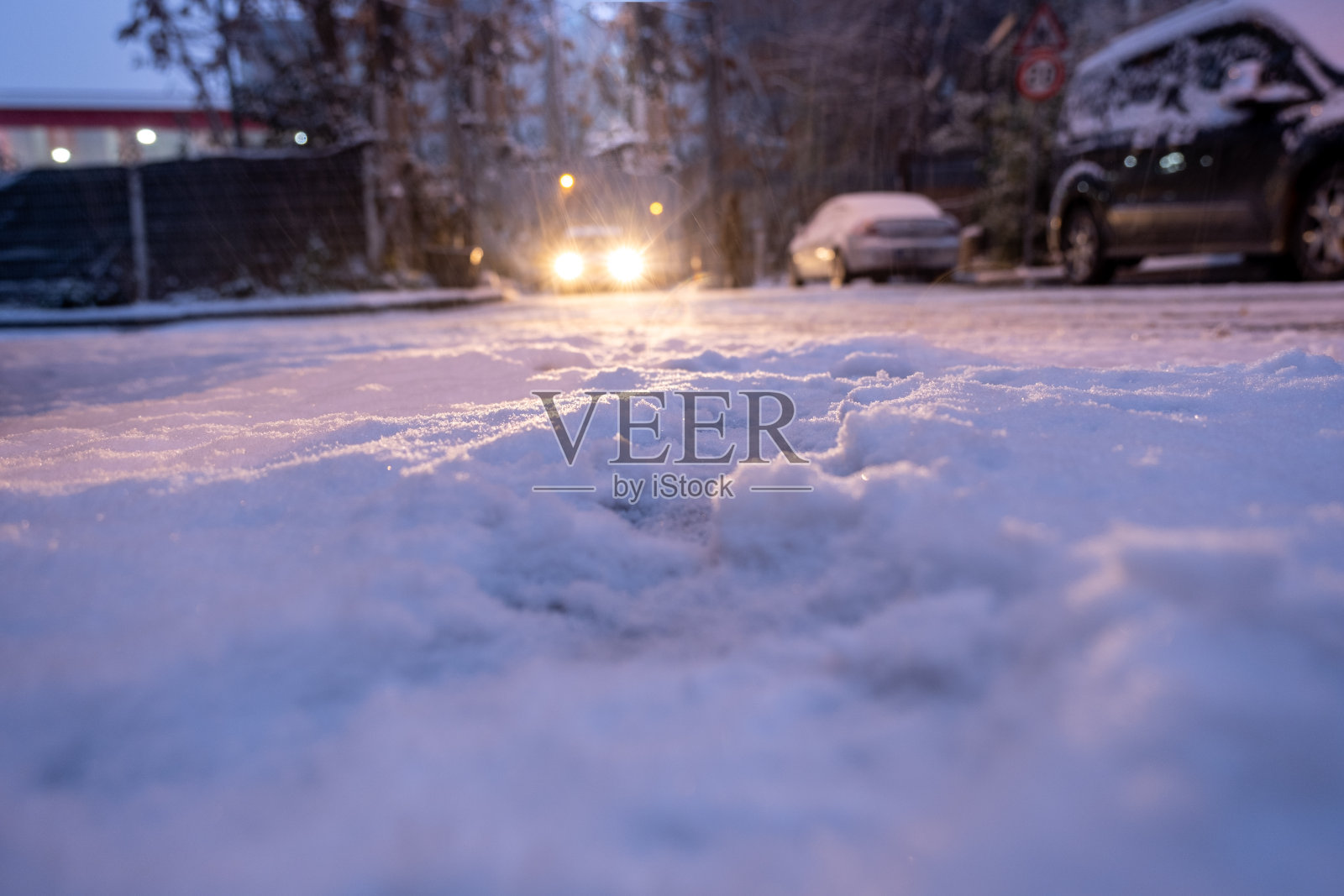 在冬天下雪的夜晚，汽车的前灯闪闪发光照片摄影图片