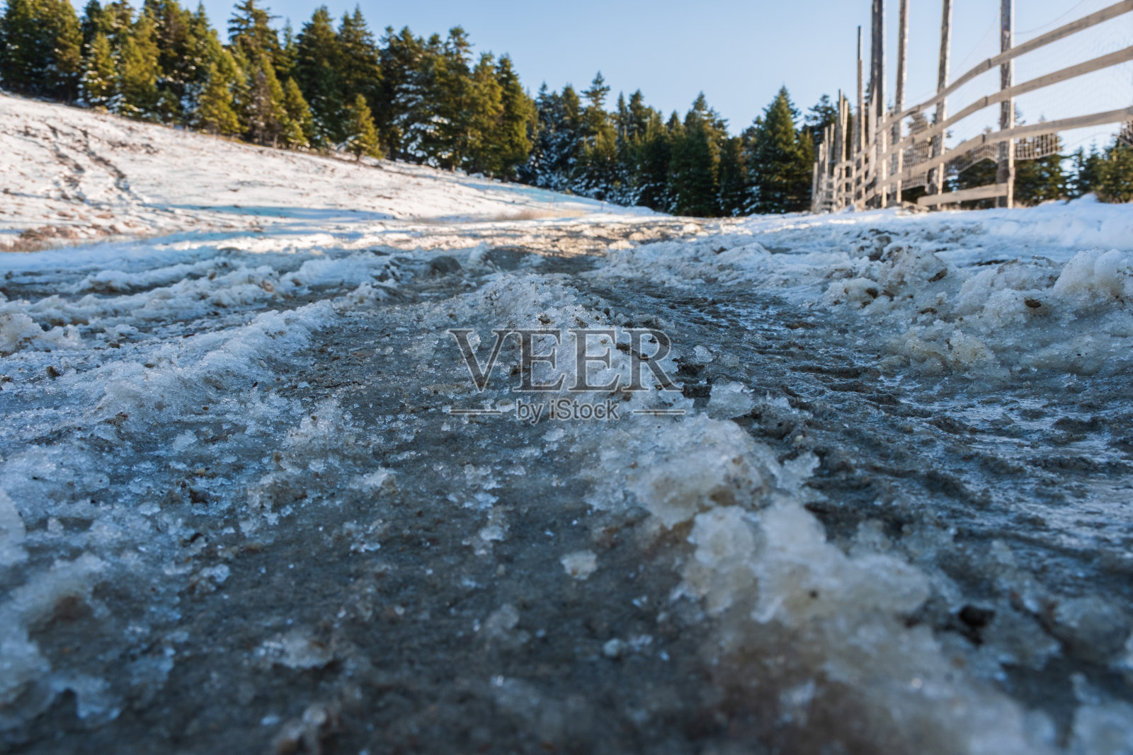 肮脏的道路被冰雪覆盖，冷杉林在冬天的时候照片摄影图片