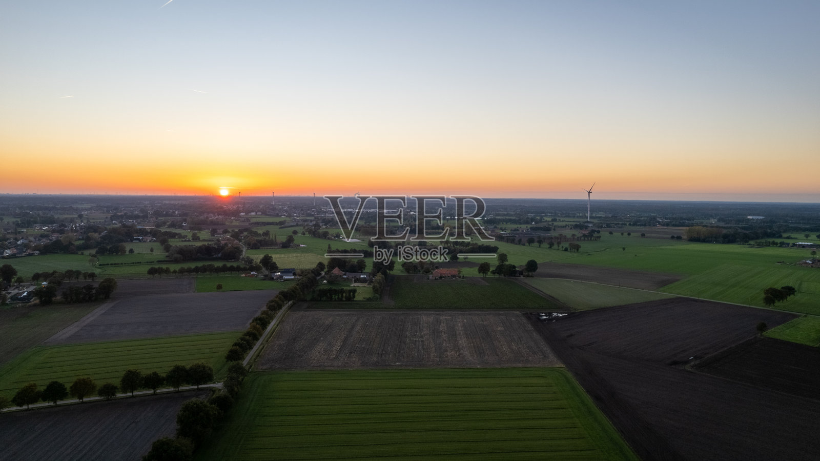 鸟瞰图，比利时日出时的乡村景色。乡村农场，玉米地，绿色的田野，阳光和雾。比利时、欧洲。照片摄影图片