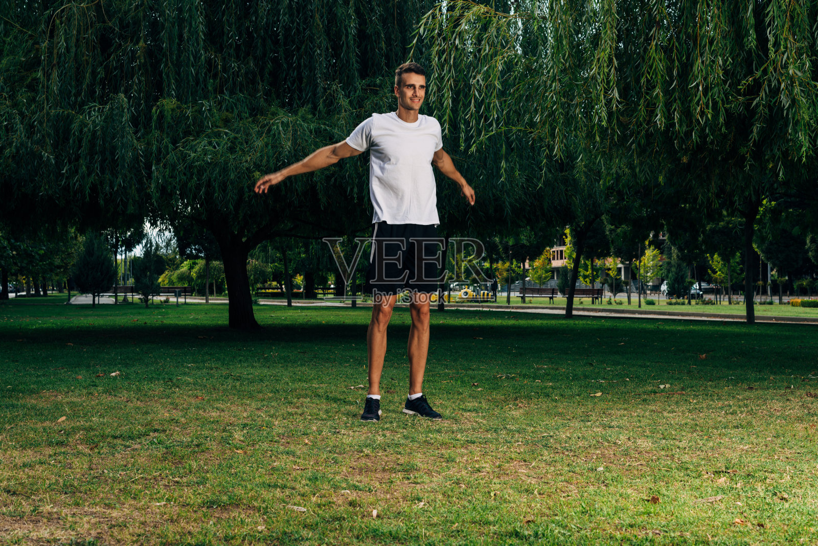 年轻人在绿色的公园里做伸展运动照片摄影图片