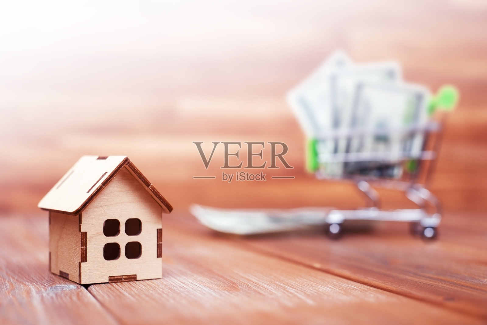 木制的房子和一堆钞票在一个木制背景的购物车里照片摄影图片