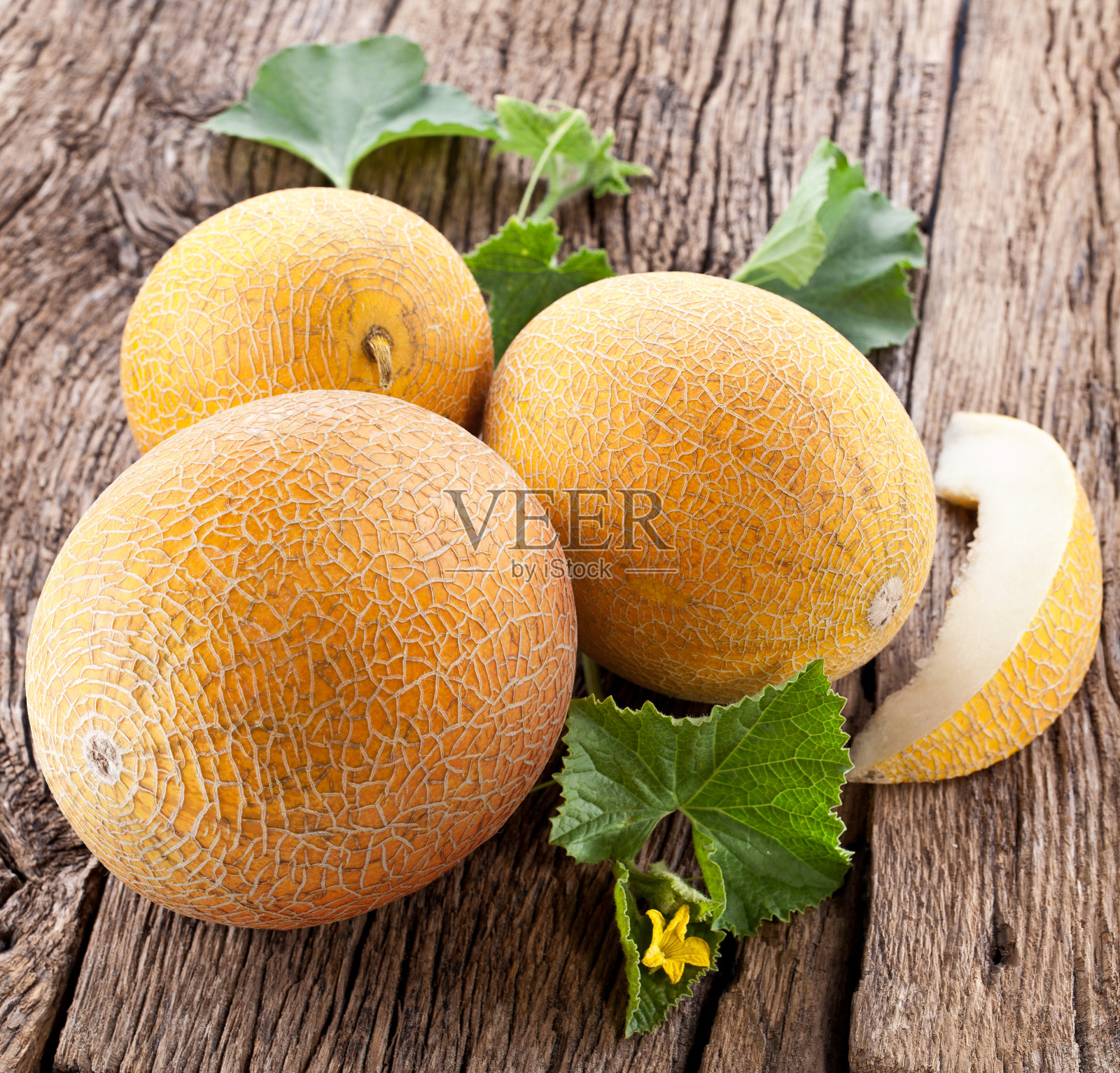 老木桌上放着熟透的黄瓜片和香瓜叶。照片摄影图片