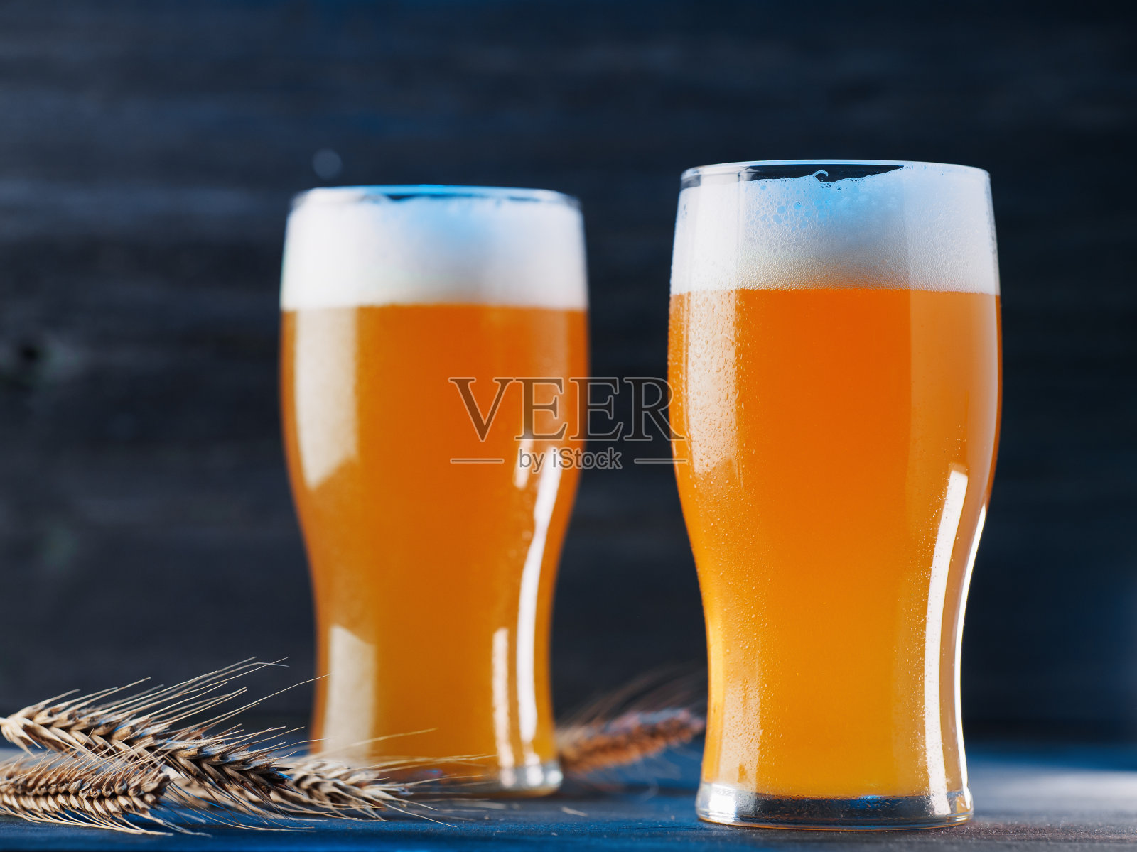 两杯冰镇啤酒，黑色木质背景照片摄影图片