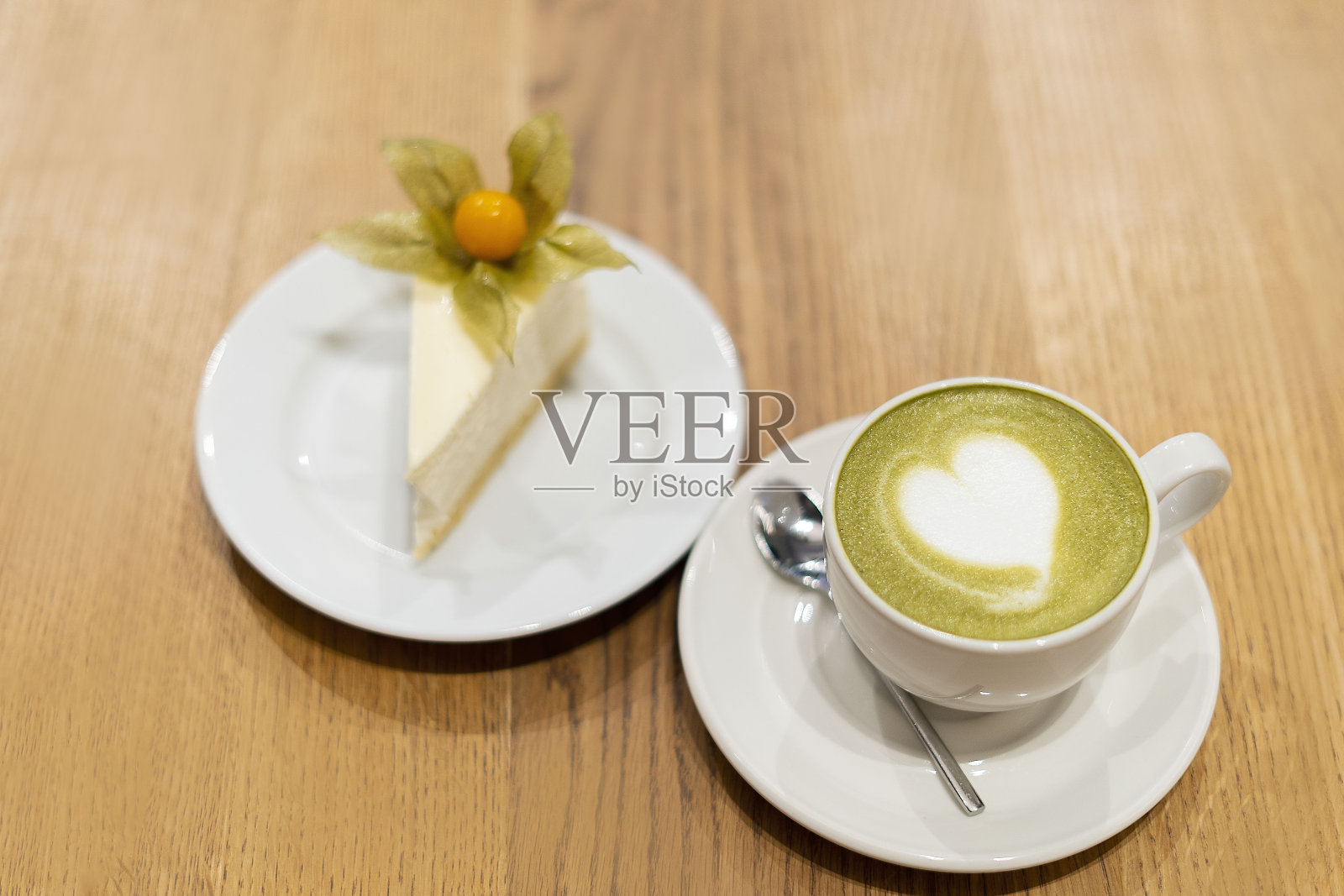 木制的表面放着一杯白色的抹茶。托盘上有一个白色的芝士蛋糕和一个浆果照片摄影图片