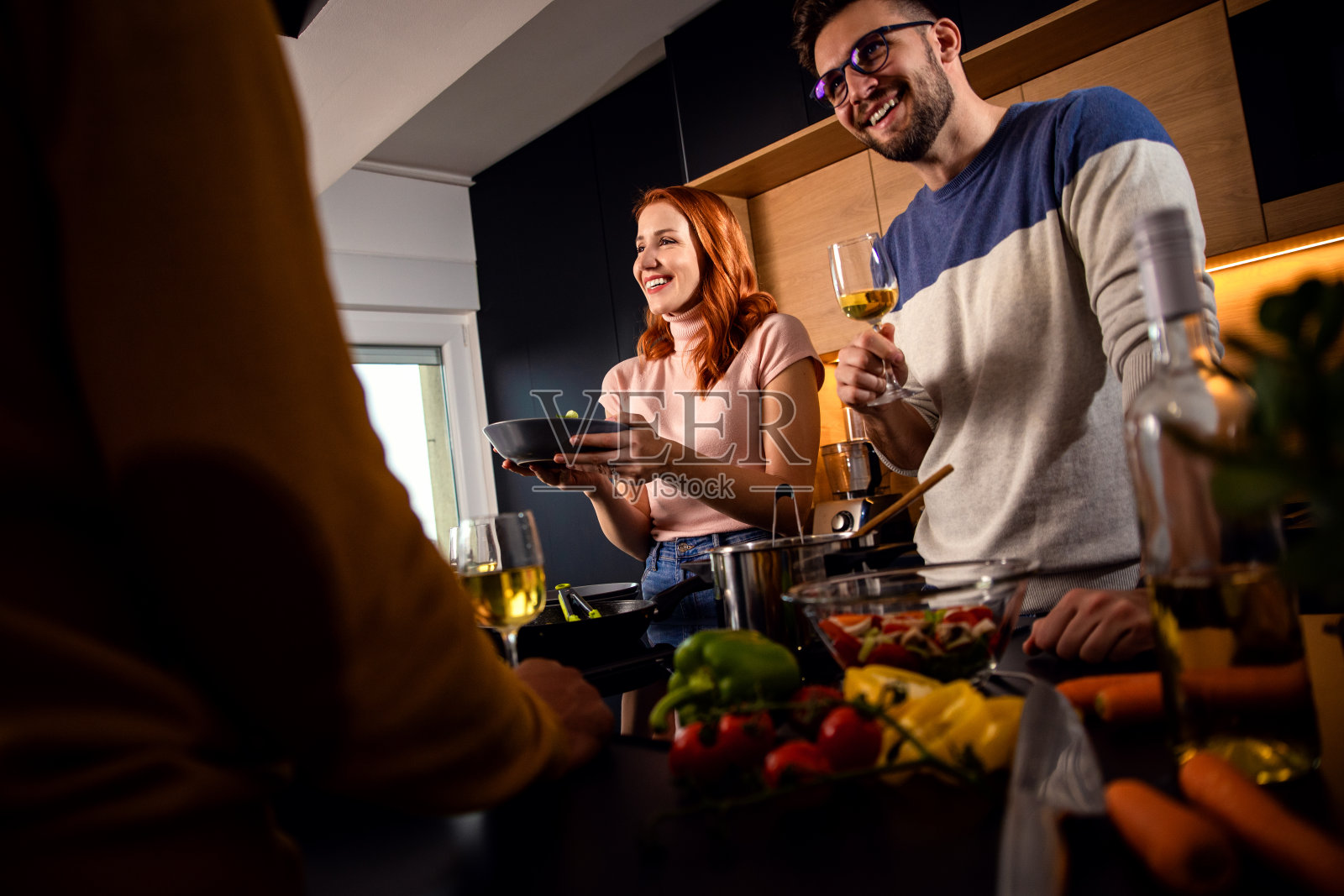 一群朋友在家里的厨房里准备素食餐。照片摄影图片