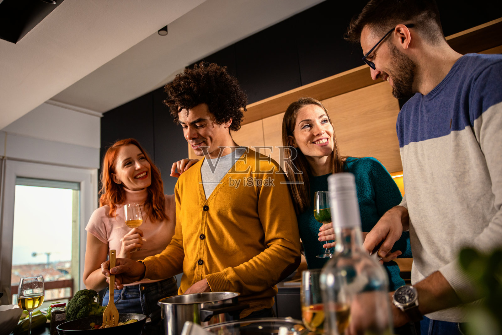 一群朋友在家里的厨房里准备素食餐。照片摄影图片