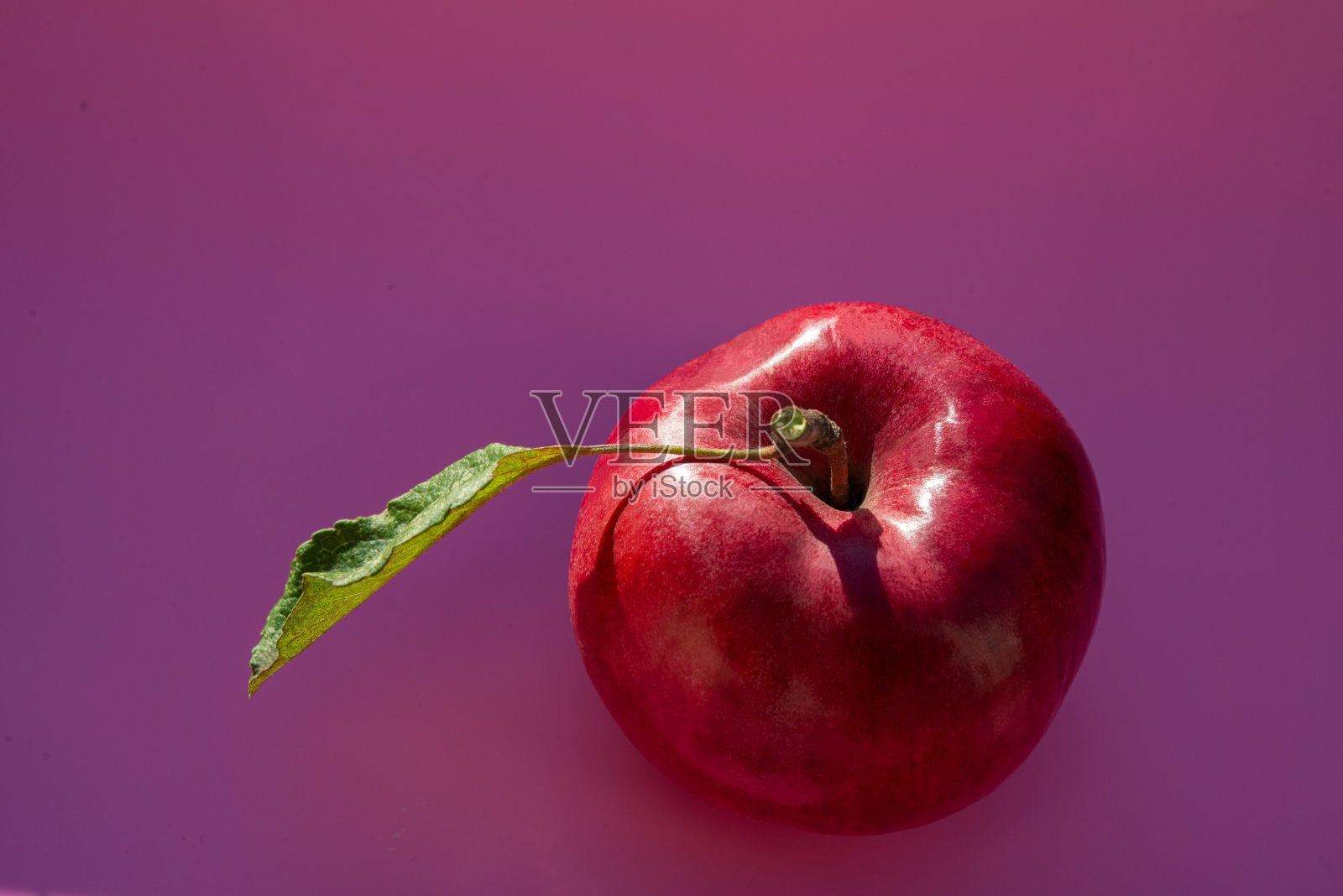 红苹果，绿色的叶子，深粉红色的背景。照片摄影图片