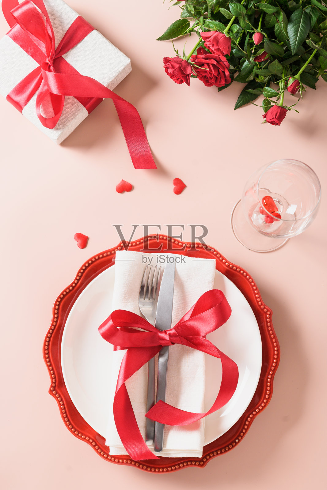 情人节的餐桌上摆放着礼物，一瓶红酒，玫瑰花，一颗心。照片摄影图片