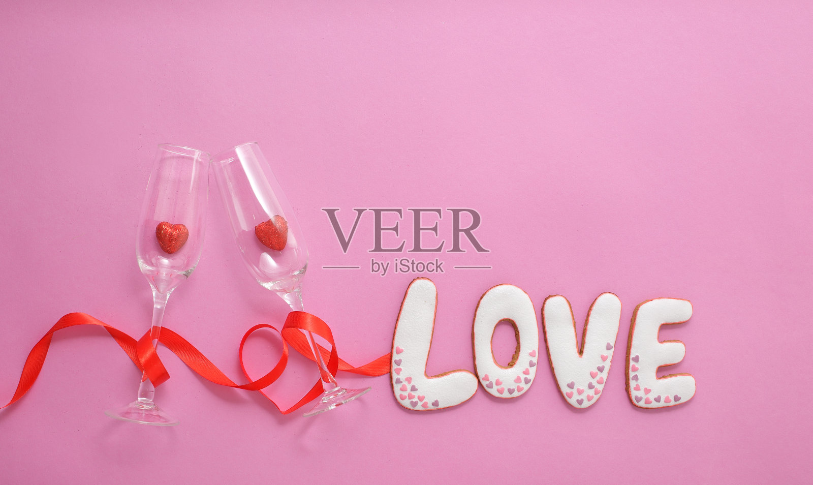 一种里面有心形的眼镜，用红丝带包裹成心形。姜饼上面写着“爱”。照片摄影图片