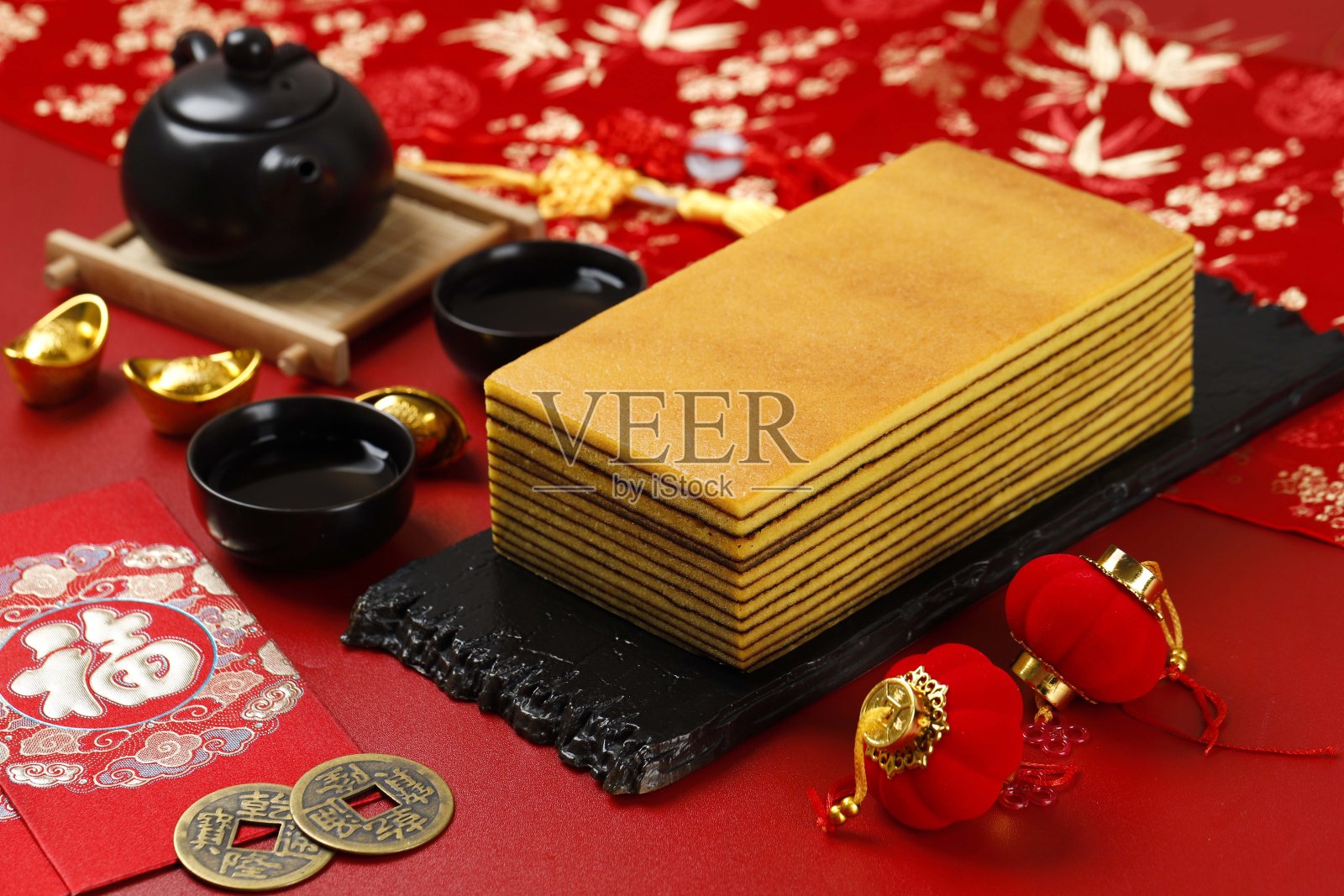 青金石，印尼传统千层蛋糕，带有中国新年红的概念。白色盘子上的切片照片摄影图片