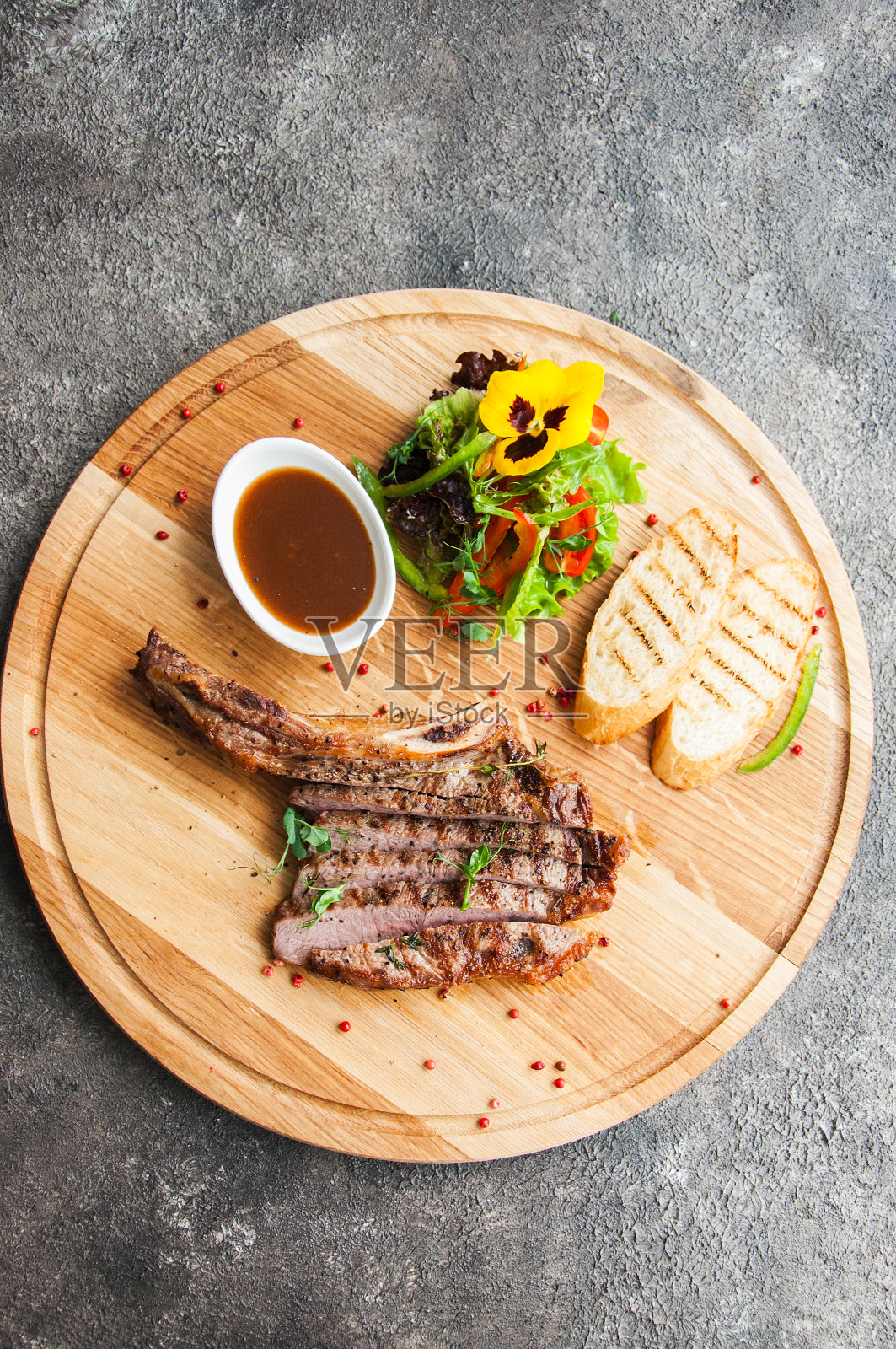 在灰色背景的木板上烤牛排。前视图。照片摄影图片