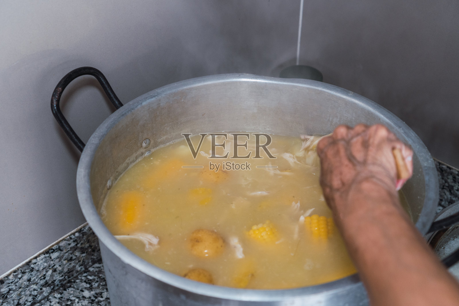 自制鸡汤。女人搅拌汤的手照片摄影图片