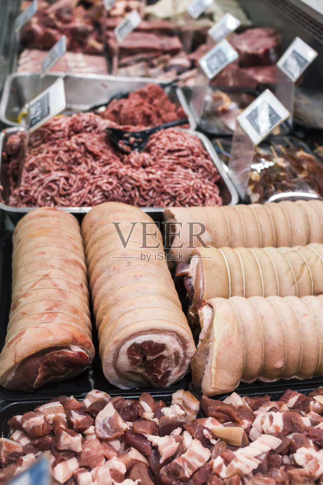 在超市或肉店里陈列各种猪肉和牛肉块。前面是火腿跗关节，后面是瘦肉碎。照片摄影图片