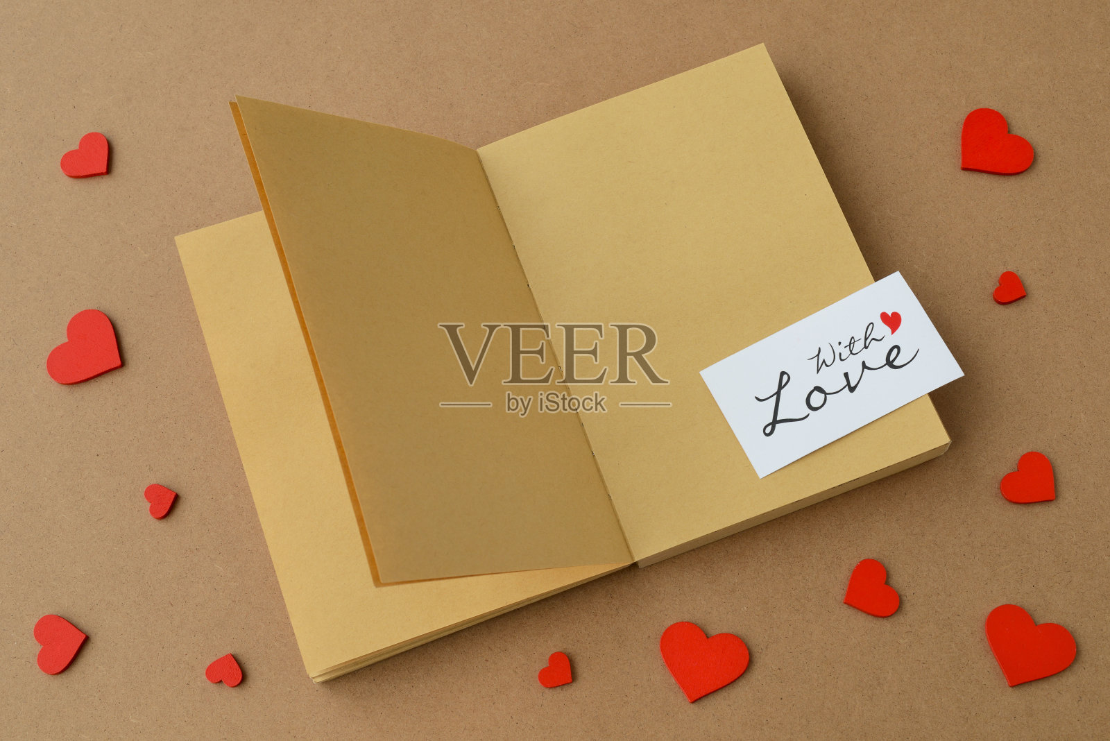 打开的书，牛皮纸做的笔记本，卡片“与爱”，桌子上的红心。情人节卡片照片摄影图片