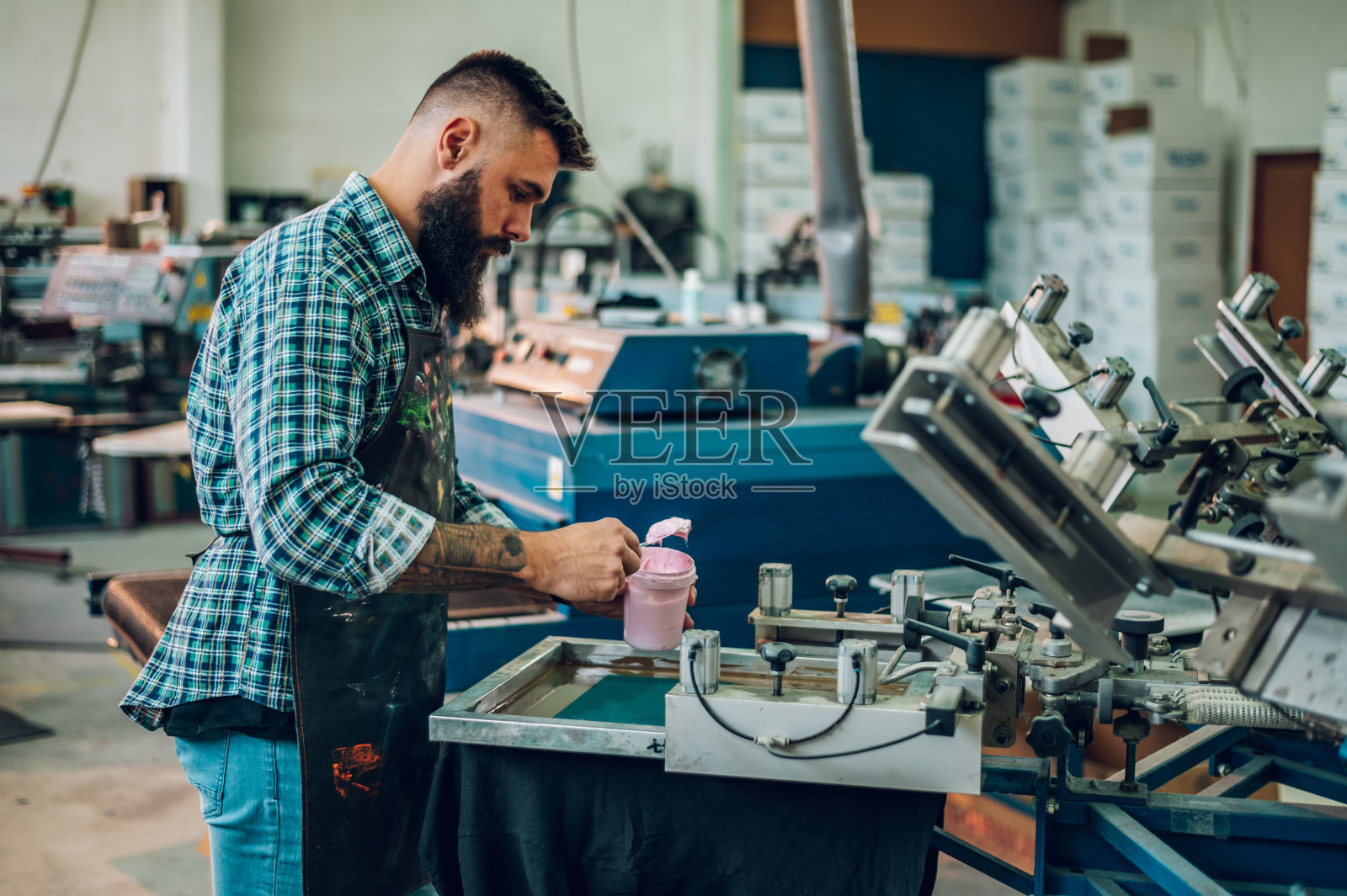 车间里，男性工人在使用印刷机时，将油墨压在画框上照片摄影图片