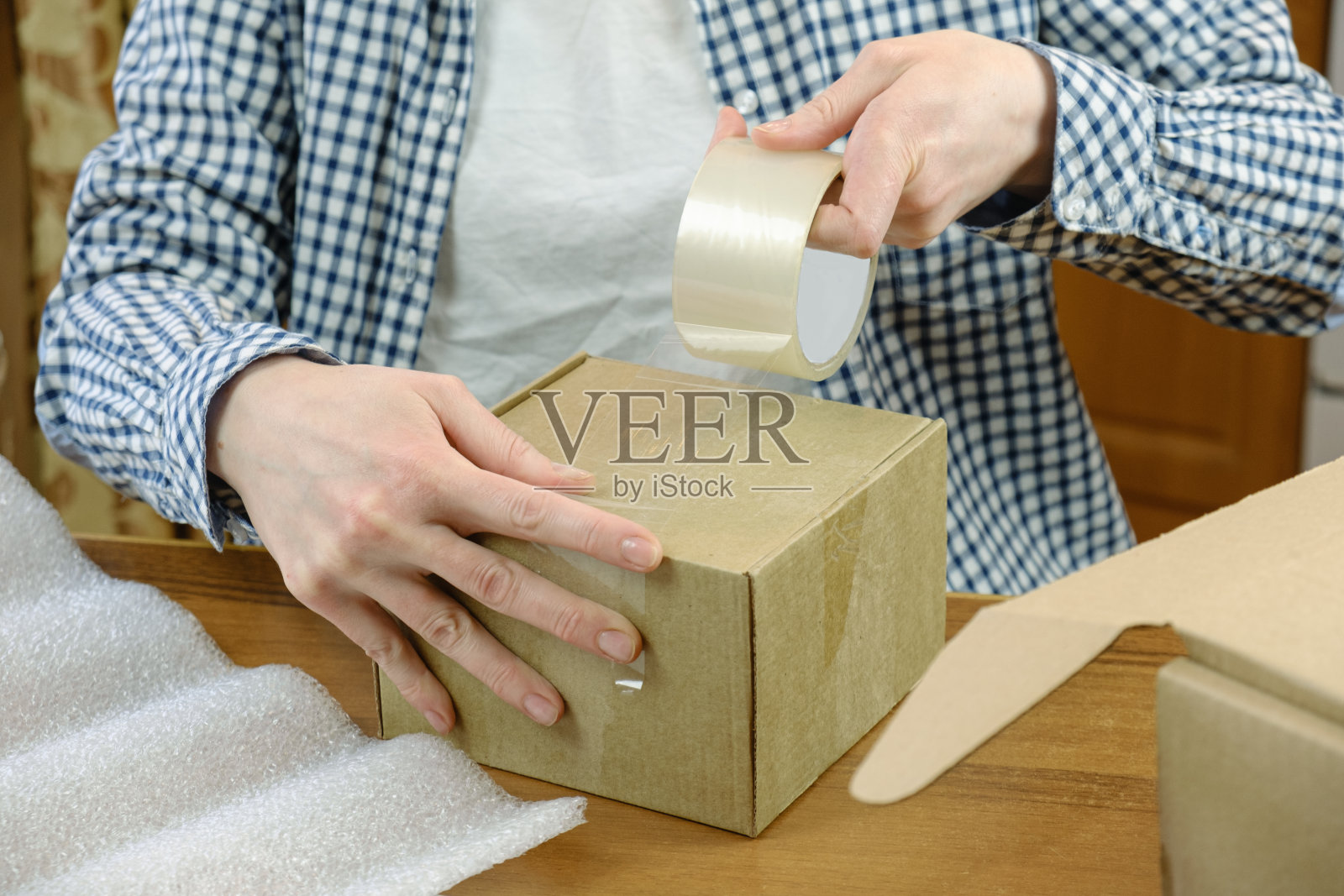 仓库员工将网上商店的订单用透明胶带包装在纸板箱里照片摄影图片