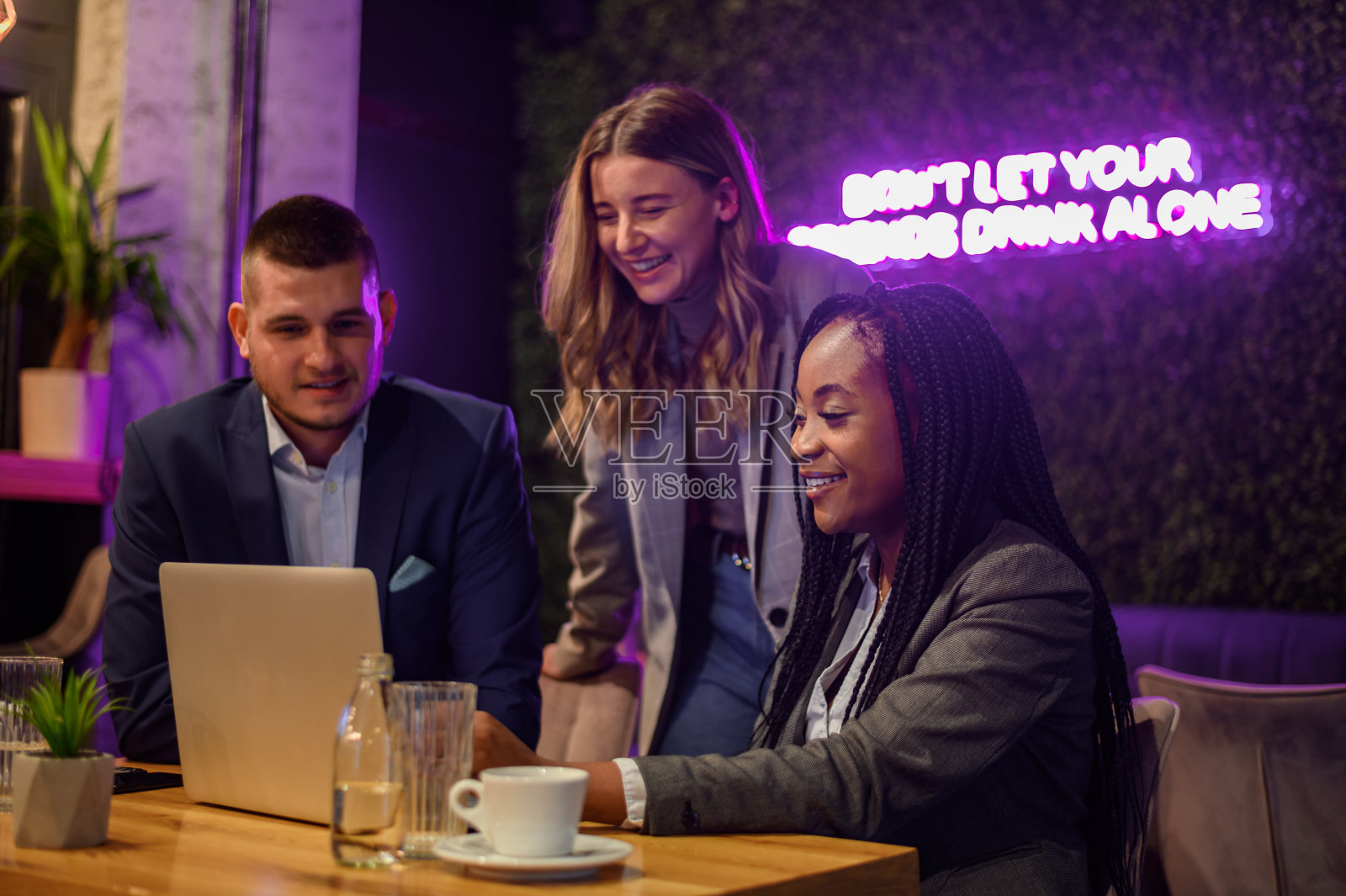 愉快的同事一边在咖啡馆开会，一边用笔记本电脑工作照片摄影图片