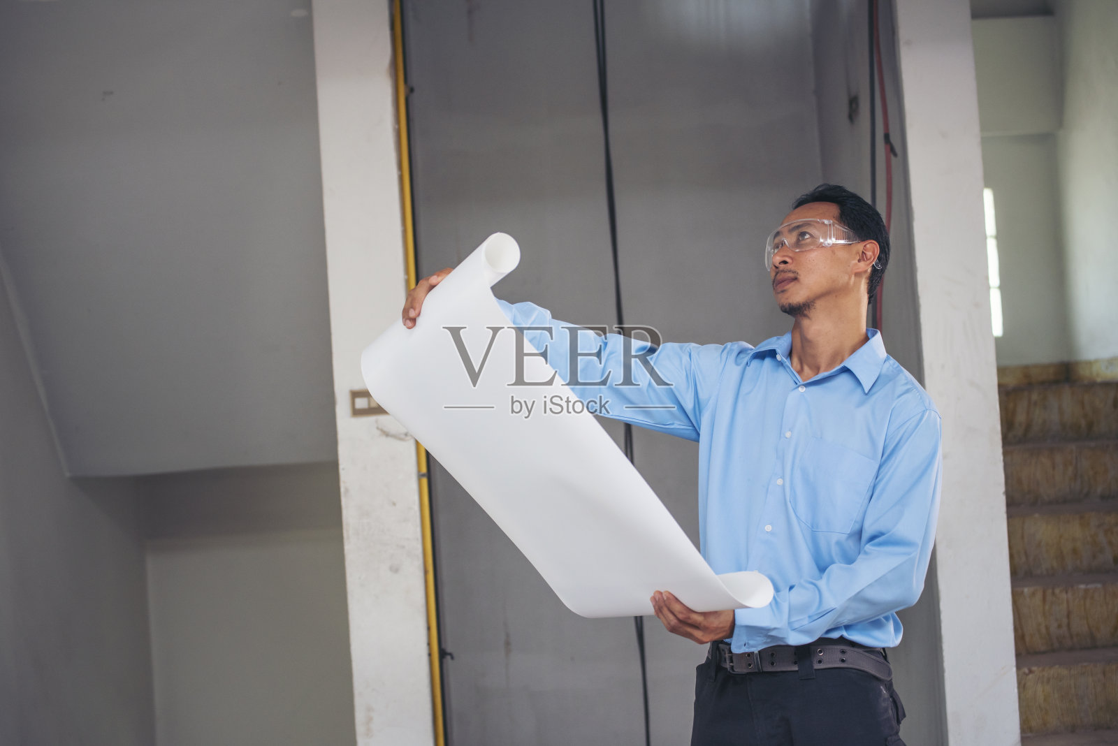 建筑工，工程师，土木工人看图纸。施工现场施工工程师手持图纸，身穿蓝衬衫安全白色安全帽。产业劳动劳动者房地产概念照片摄影图片