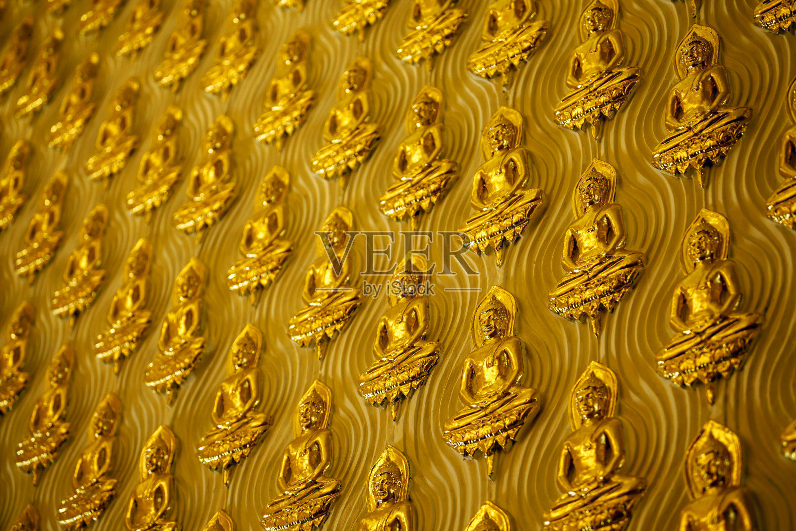 黄色的墙壁上装饰着金色的小佛像。照片摄影图片