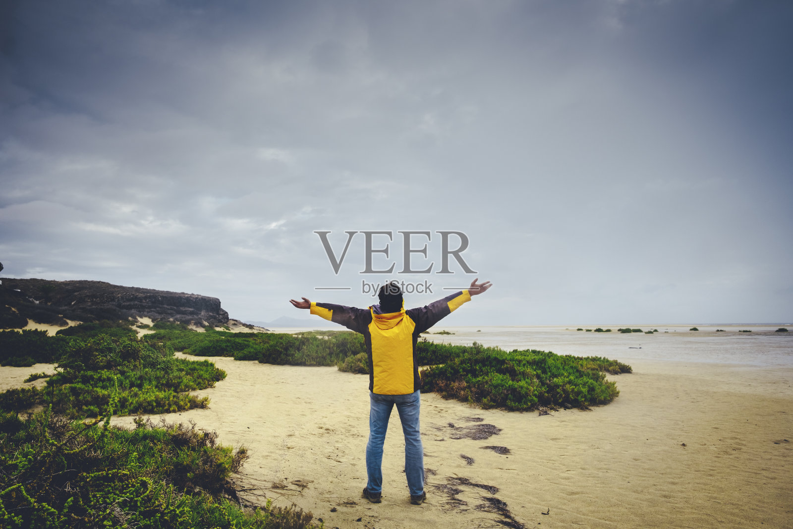 一个男人站在沙滩上伸展双臂的背影。探索和冒险的生活方式的人们。旅游男性享受自然照片摄影图片