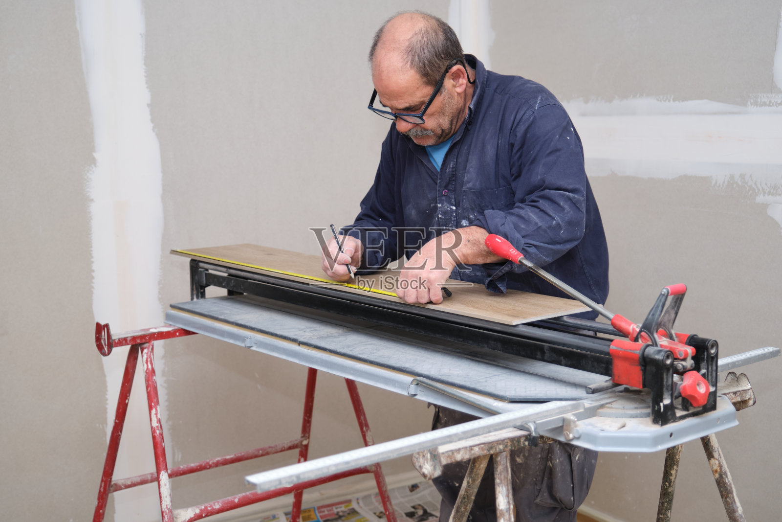 承包商在切割前测量了一块陶瓷木纹效果砖。照片摄影图片