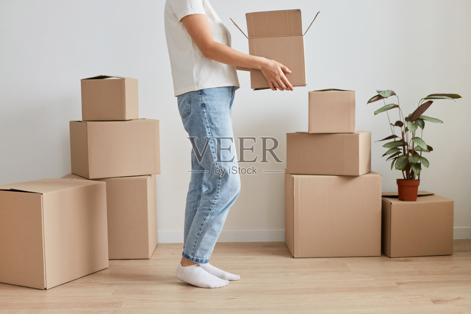 不知名的、不知名的、不知名的女人的肖像，穿着牛仔裤搬到新地方，拿着带东西的纸箱，搬迁，租或买新公寓。照片摄影图片