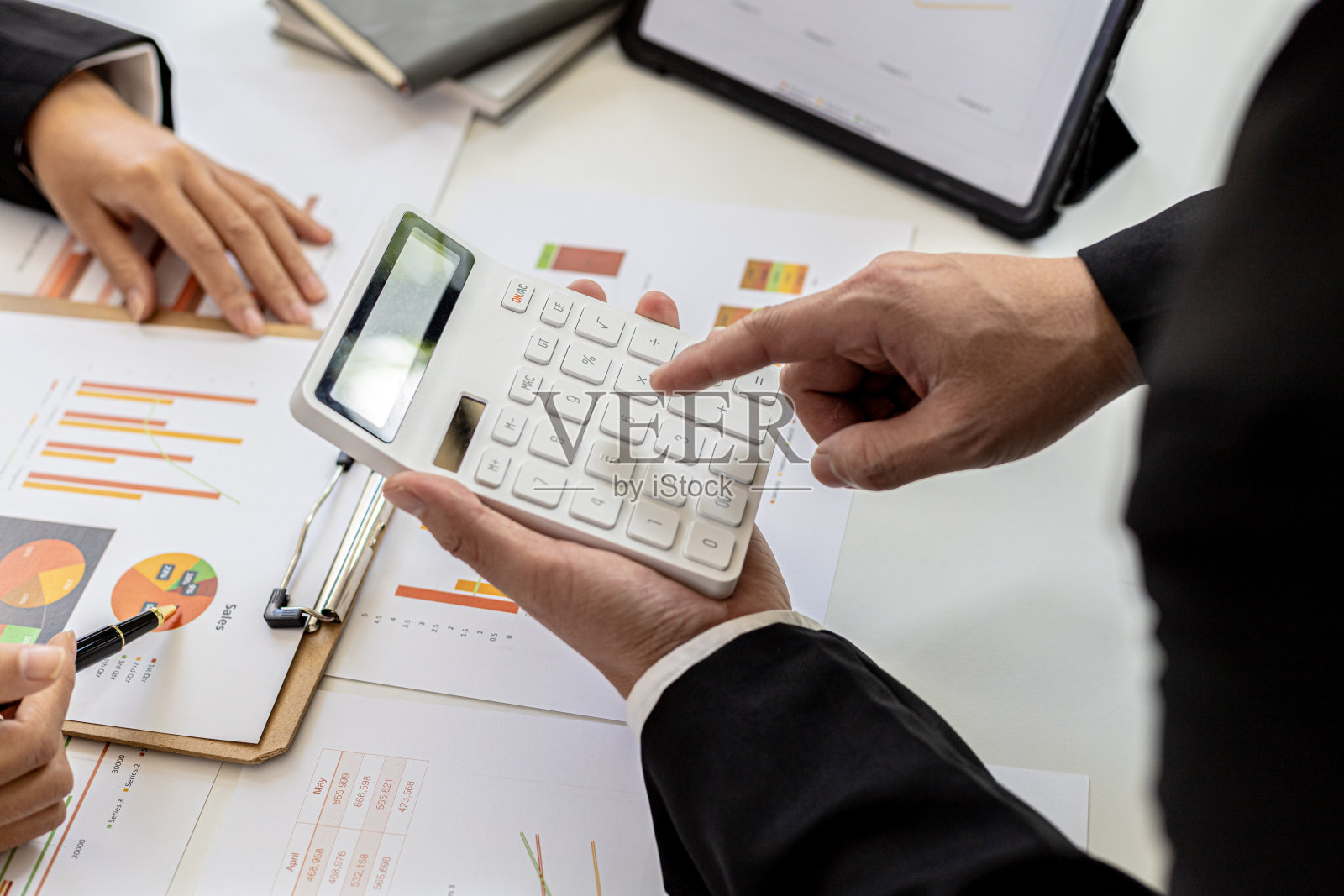 两个人用计算器在文件上核对数字，商业人士头脑风暴以解决亏损和制定策略以保持公司盈利和增长。照片摄影图片