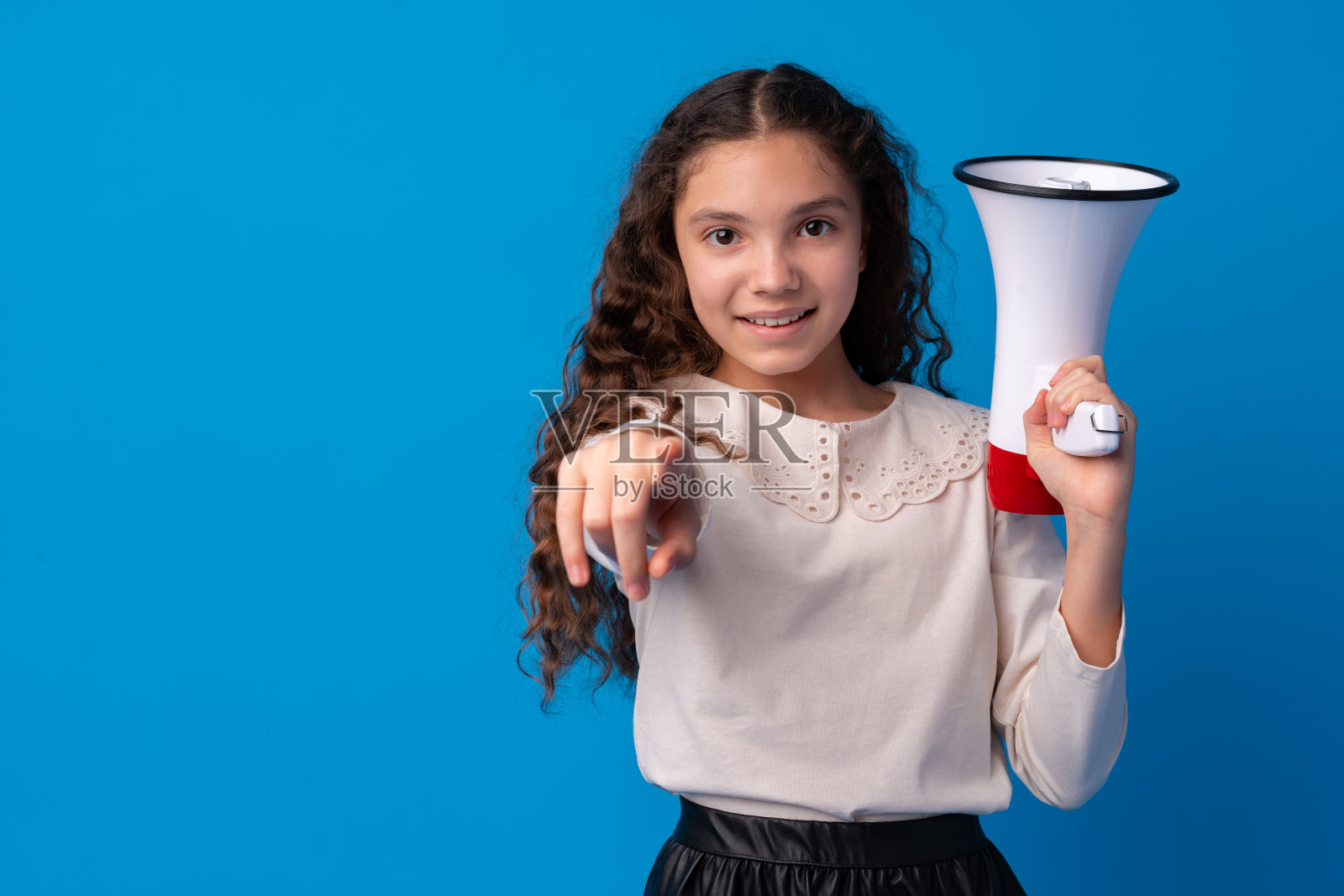 可爱的女学生拿着扩音器在蓝色的背景下照片摄影图片