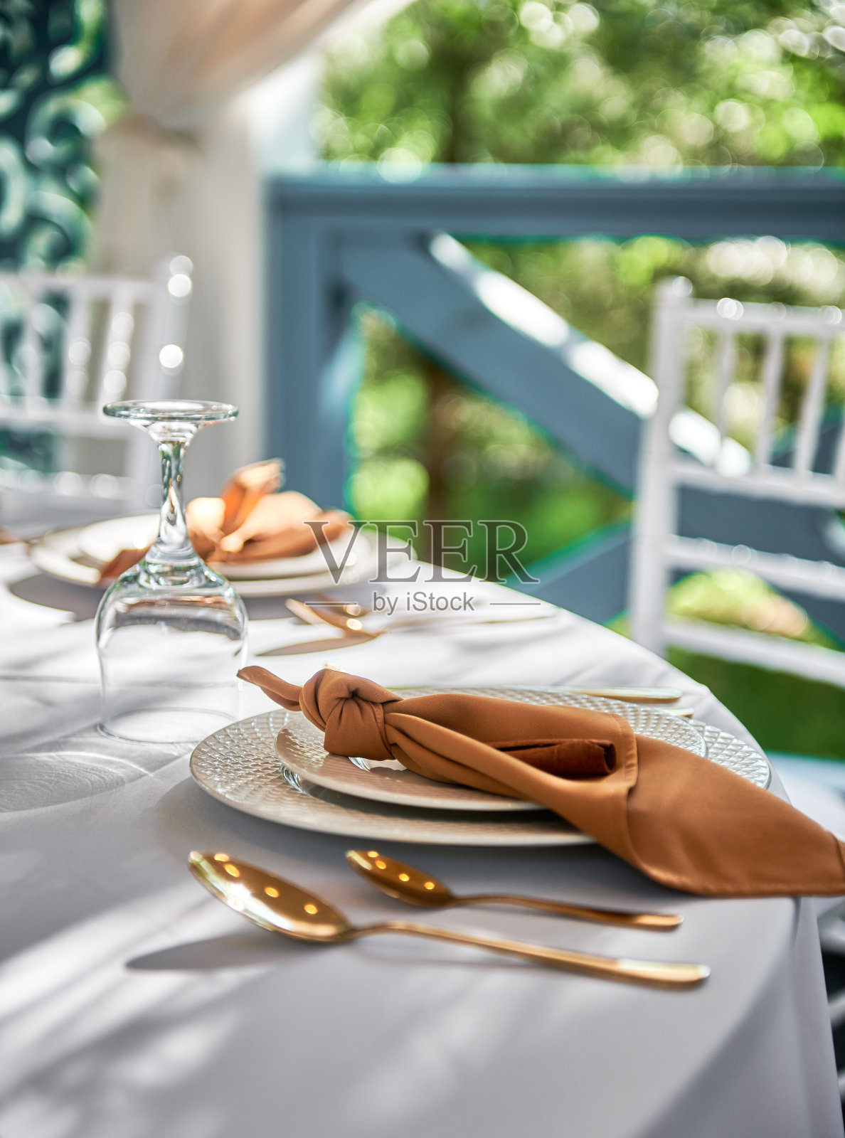 餐桌设置起泡的葡萄酒杯，盘子与棕色餐巾和餐具在桌子上，复制空间。在婚宴上放置。餐厅婚宴餐桌照片摄影图片