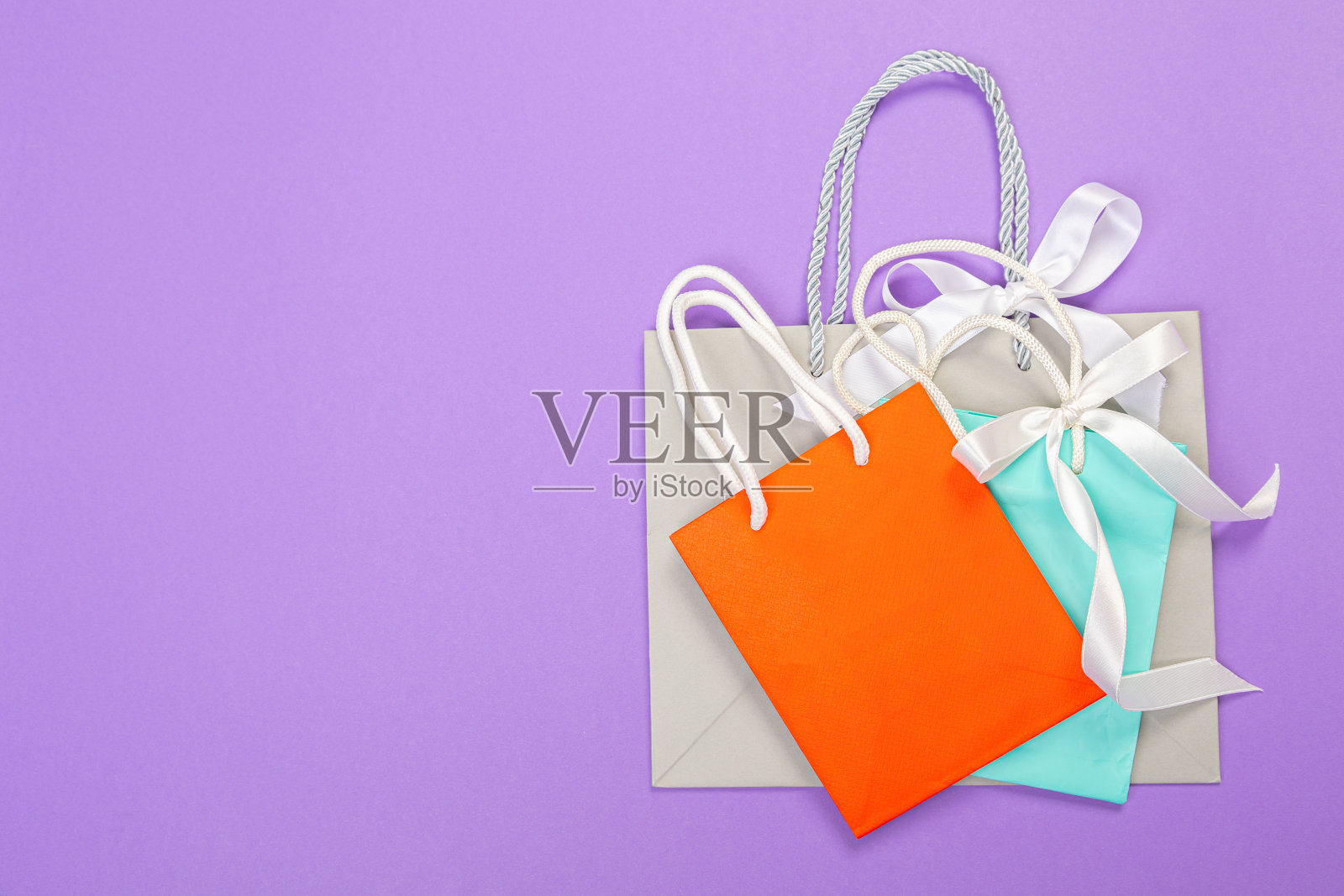 彩色生态纸购物袋在紫色的背景。关闭模拟设计和文本模板。照片摄影图片